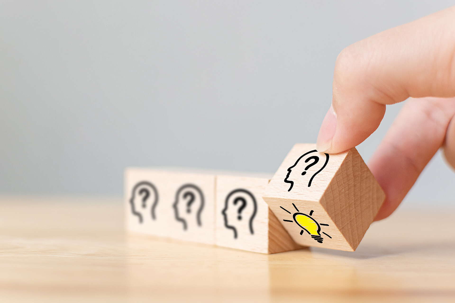 木制桌子上的手拿着方块概念、创意和创新.用人头符号和灯泡图标翻动手推木制立方体块