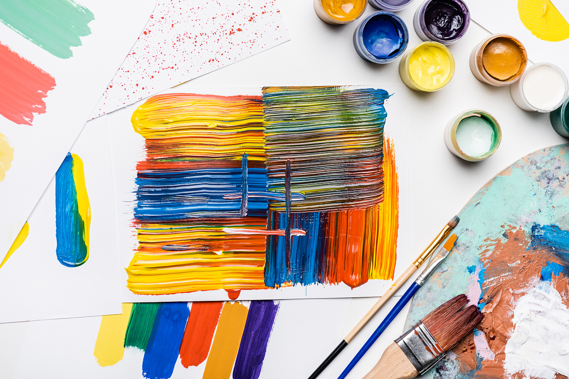 白色桌子上用画笔画下的油彩白色背景下的粉刷、画笔和抽象彩绘笔画的顶部视图