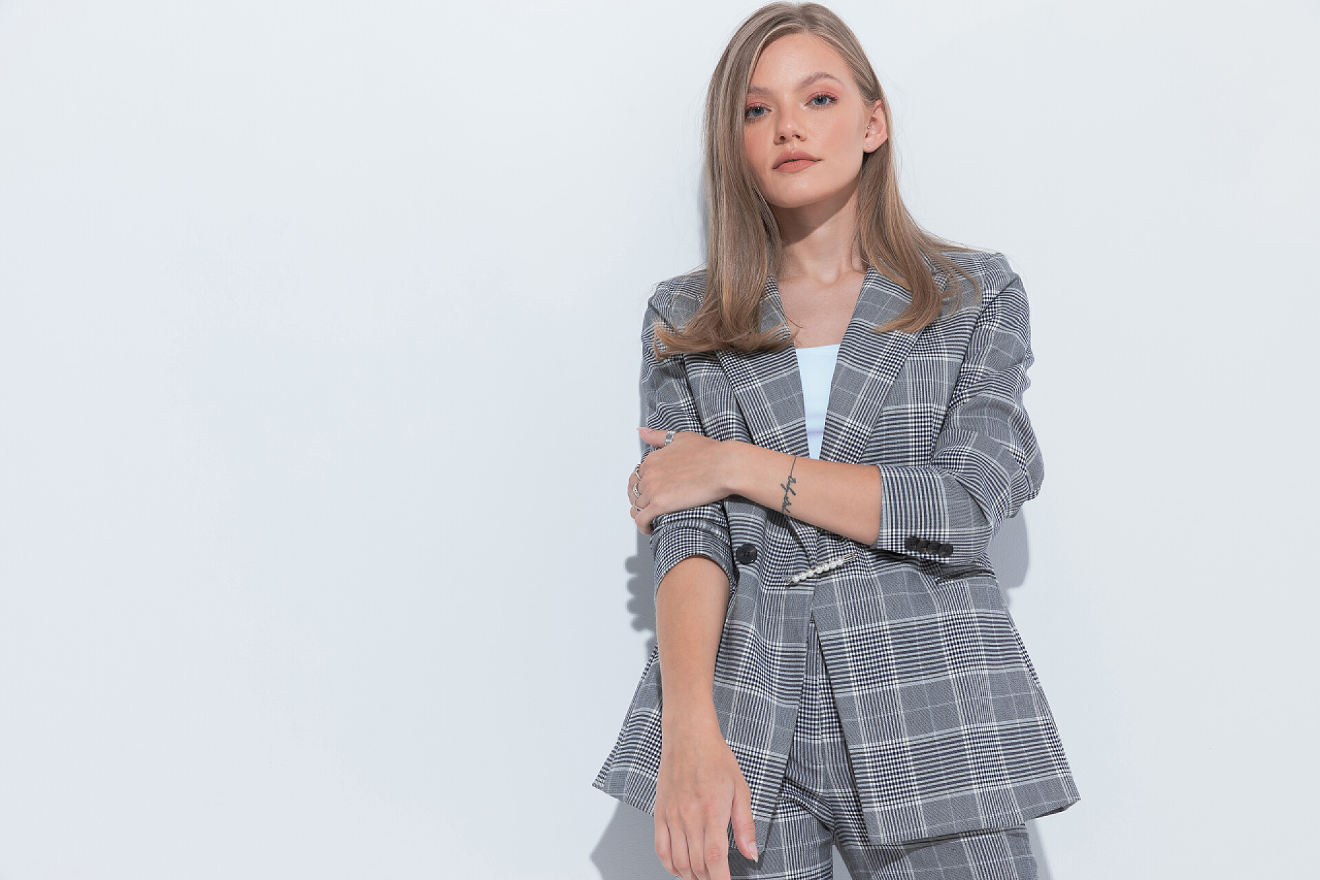 白色背景前一个美丽的女人在拍照严肃的时尚女商人向前看，穿着西服，站在白色工作室的背景上