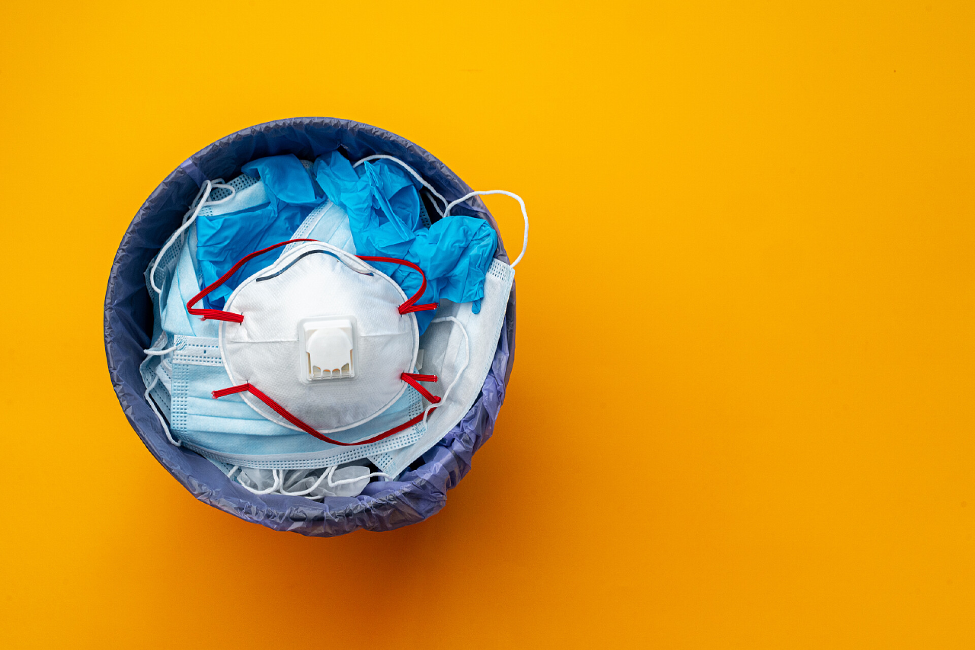 黄色背景上垃圾桶里的医用垃圾在垃圾桶内使用过传染病口罩和医疗手套