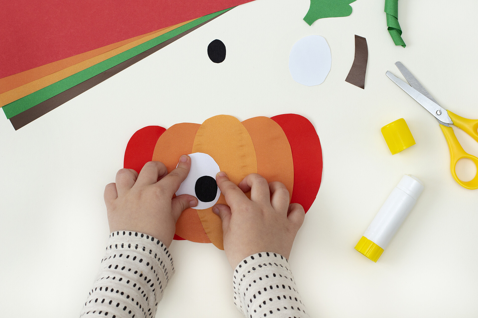 在桌子上制作彩纸的南瓜如何把彩纸做成有趣的南瓜.最初的儿童项目。一步一步的照片说明。孩子们为万圣节准备的手工艺品。第4步