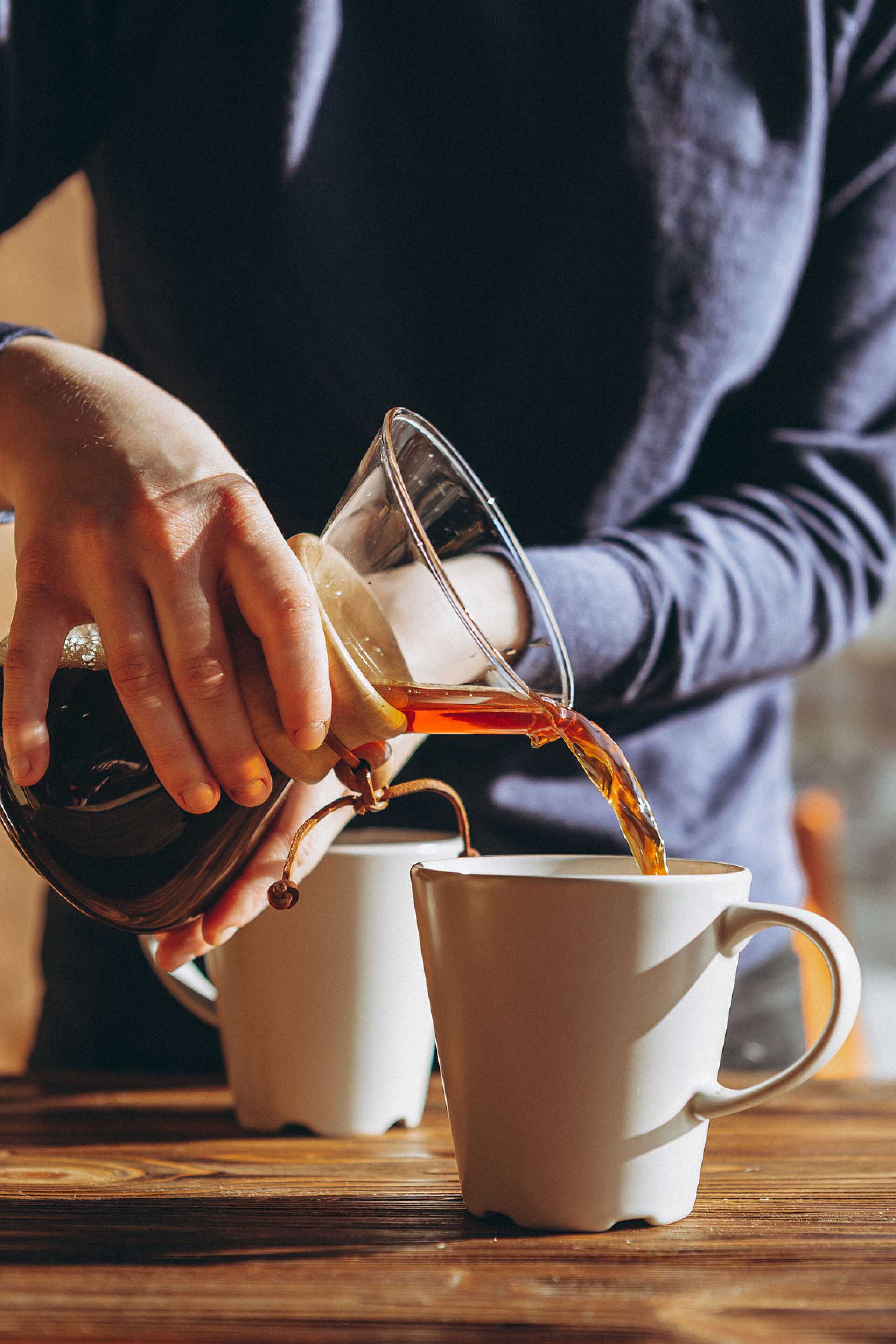 一个女人在倒咖啡咖啡的另一种方法是使用纸片过滤器，然后从瓶中倒入一个杯子。第三波咖啡店