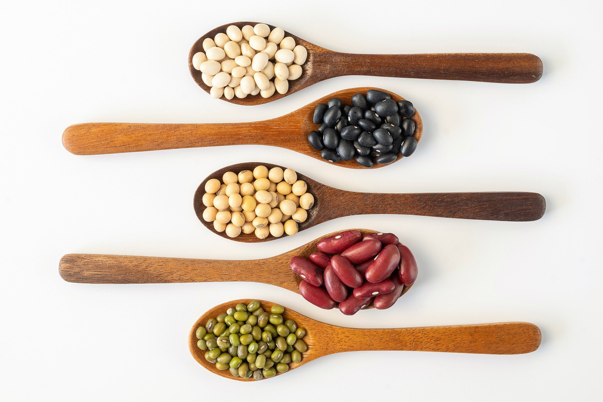 在桌子上勺子里的粮食收集从白色背景分离出来的全麦种子。健康饮食原料.