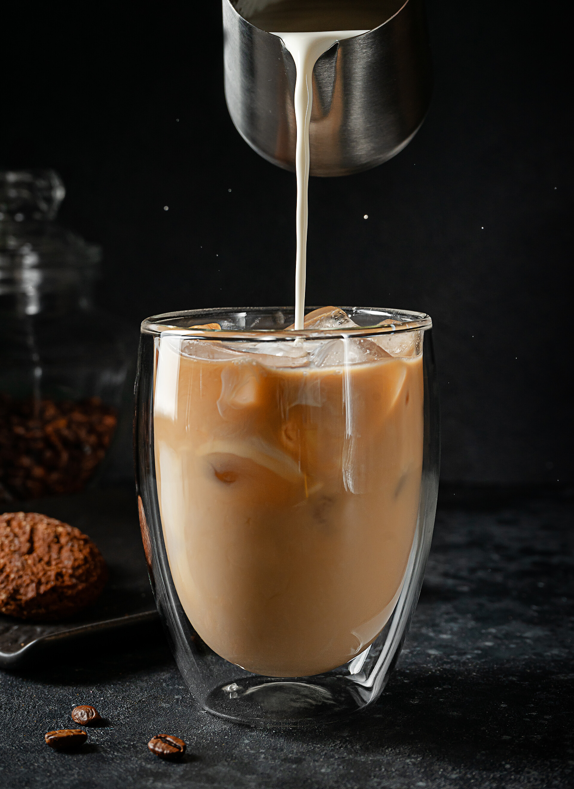 黑色桌子上的咖啡在黑色背景的冰镇咖啡中倒入奶油.