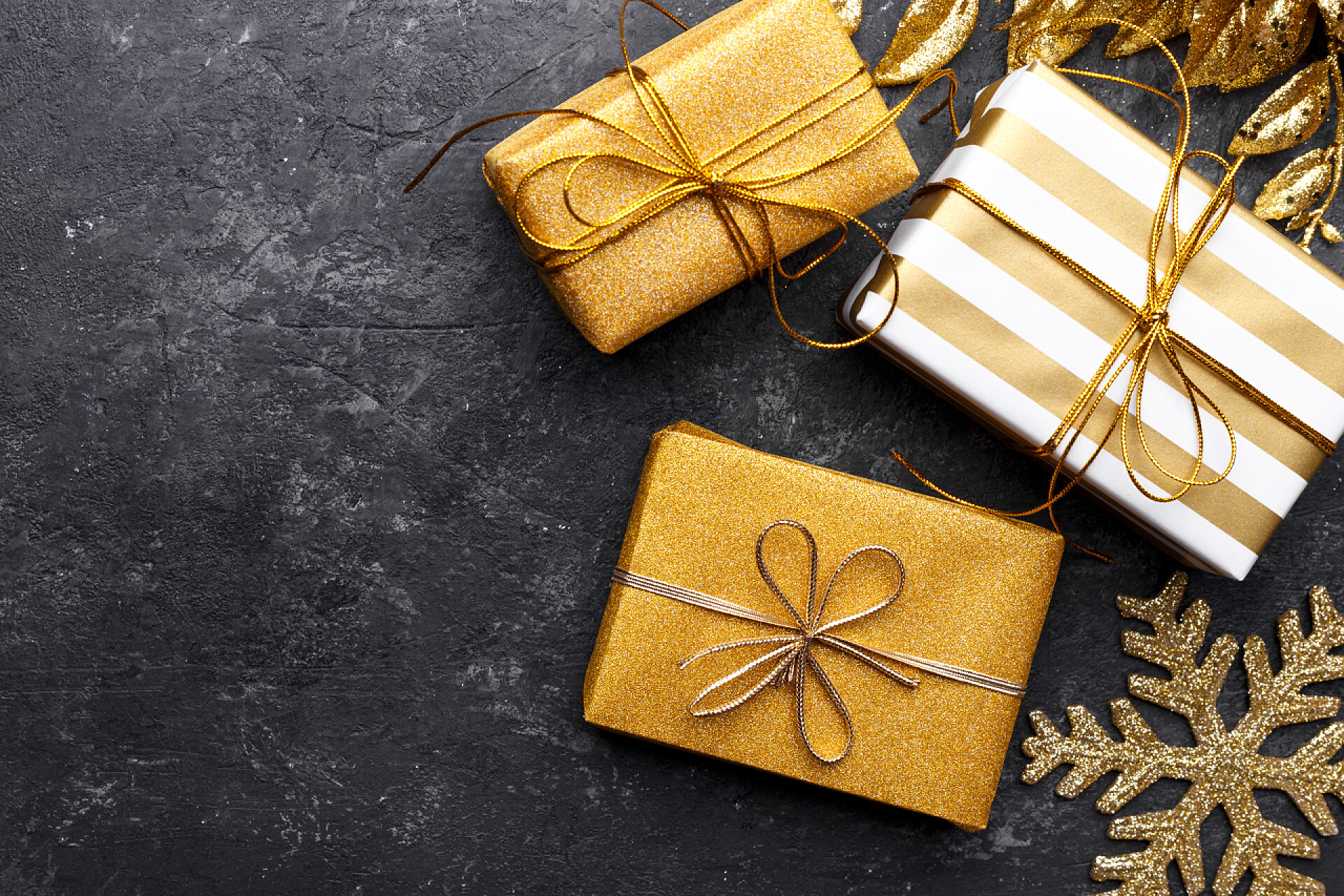 黑色桌子上的礼盒黑色石头背景的金色礼品盒，复制空间平铺，圣诞贺卡