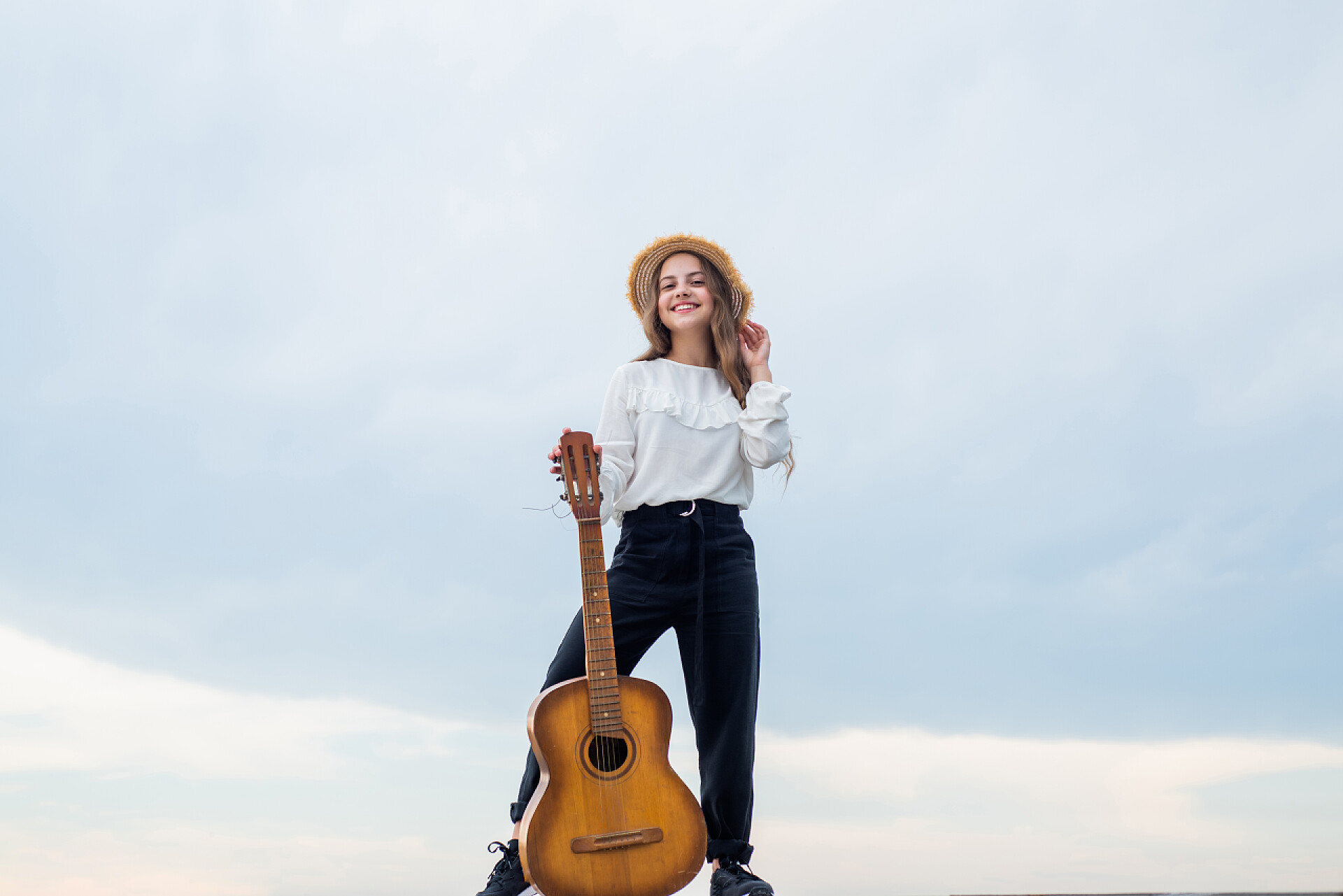 蓝色背景前拿着吉他的女孩我的吉他带着音响弦乐器的孩子。玩得开心点。吉他手或吉他手。带着吉他的快乐歌手女孩弹吉他。音乐学校的概念。乡村音乐。音乐是我的生命