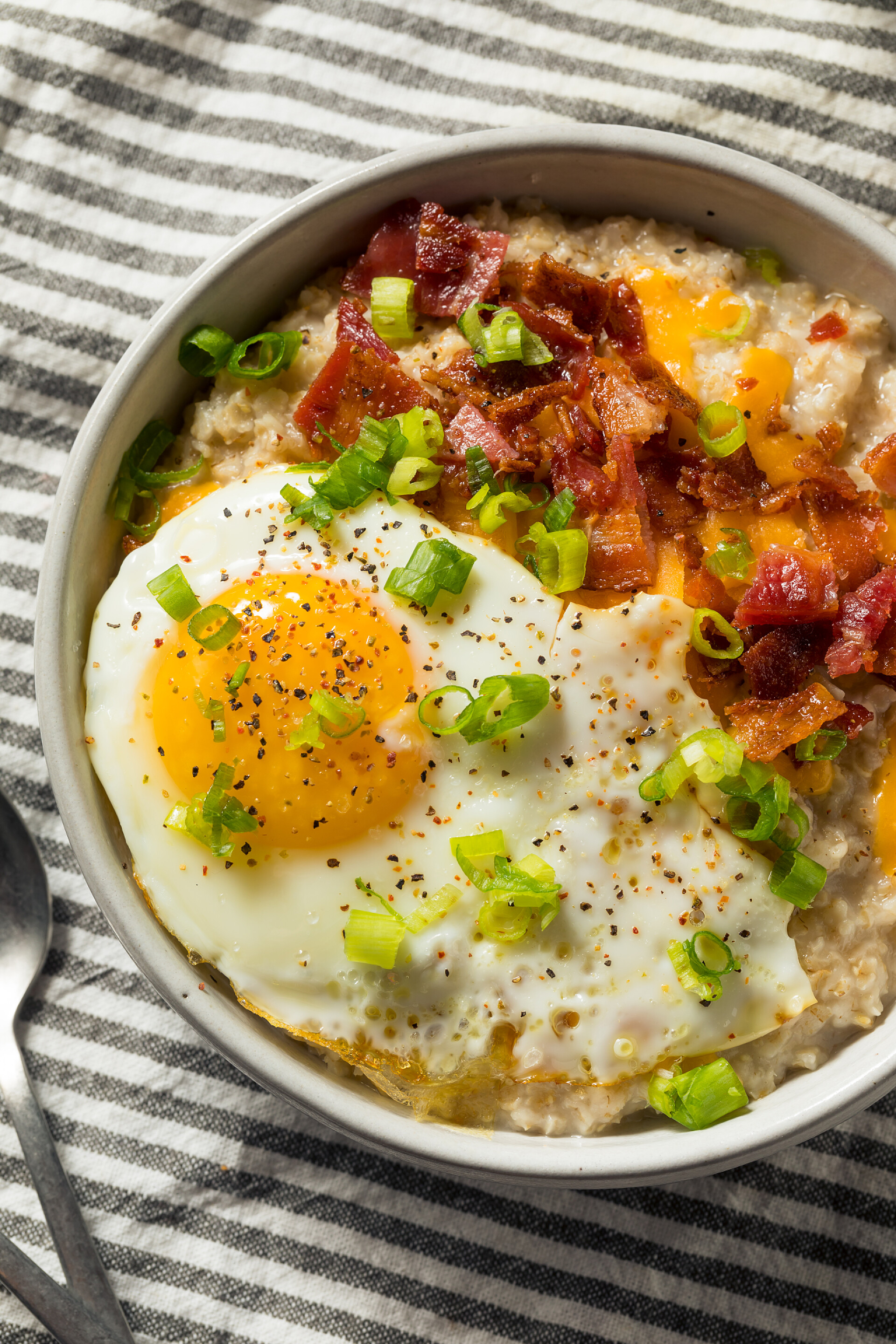 在白碗里的美味拌饭健康的家庭自制燕麦早餐与鸡蛋和培根