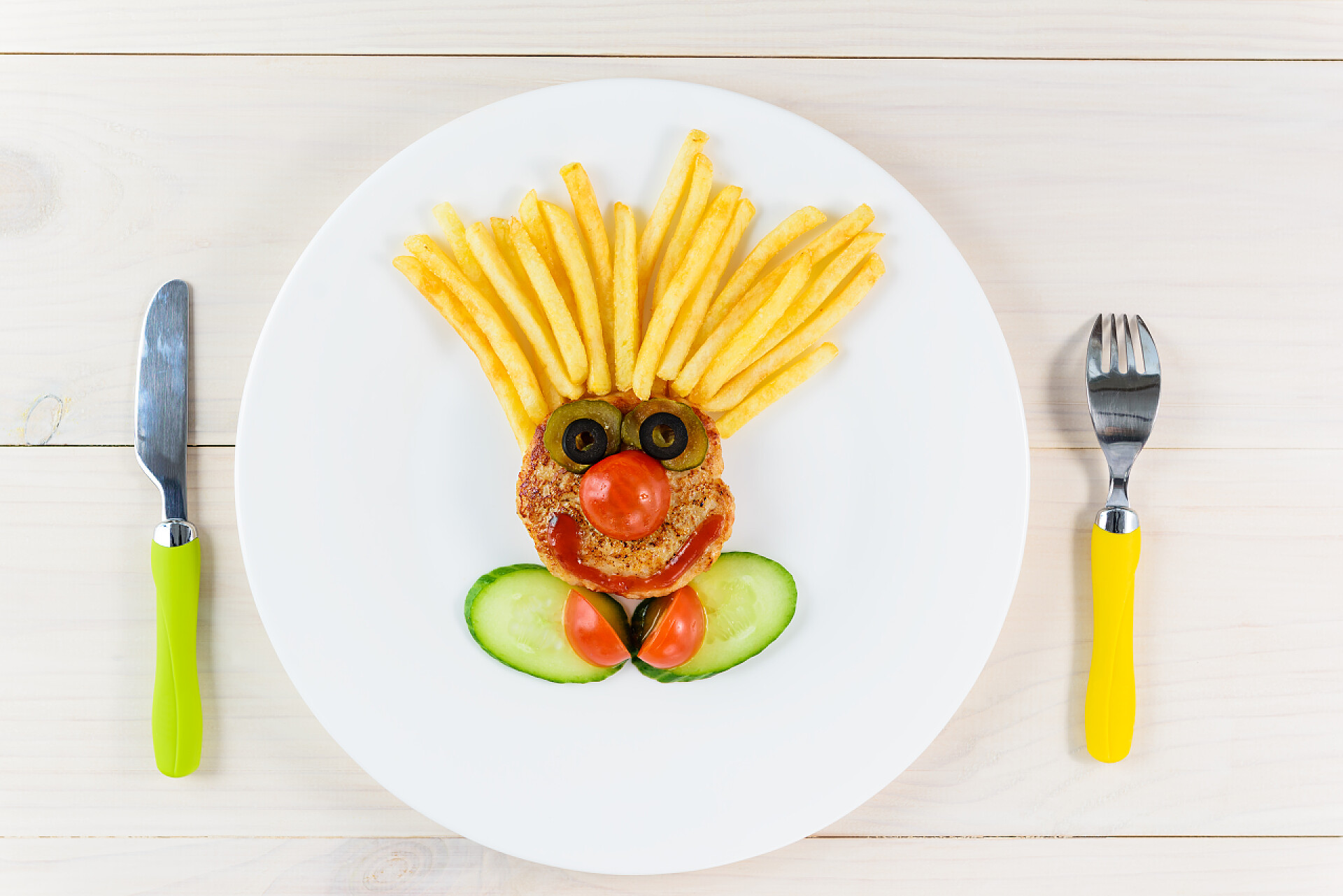 给儿童准备的食物儿童节目，以小丑的形式出现，在木制背景上架着刀叉.