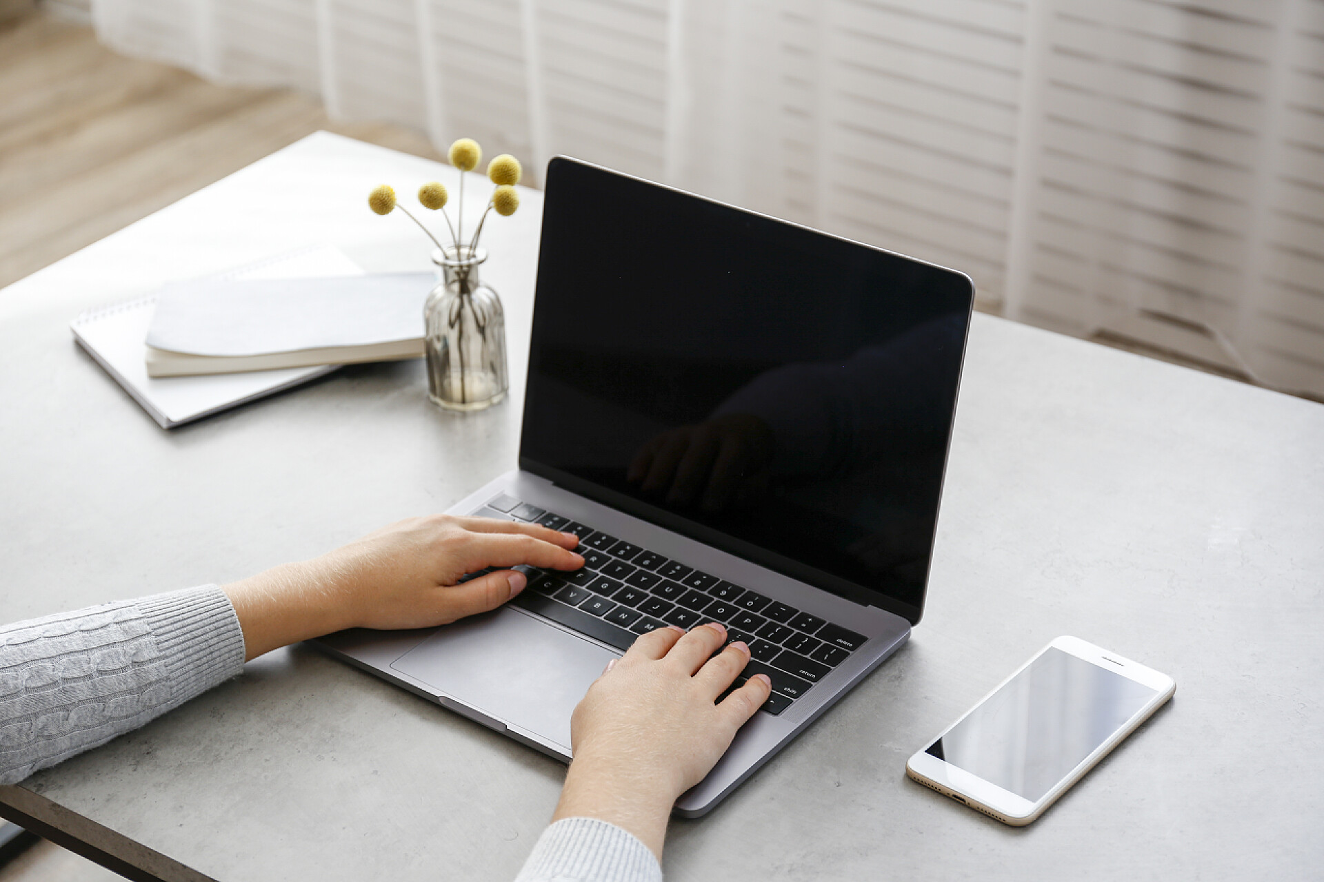 白色桌子上的电脑从家里工作的概念。在笔记本电脑上裁剪的妇女双手打字的照片。在客厅工作的女自由职业者。关闭，复制文字空间.