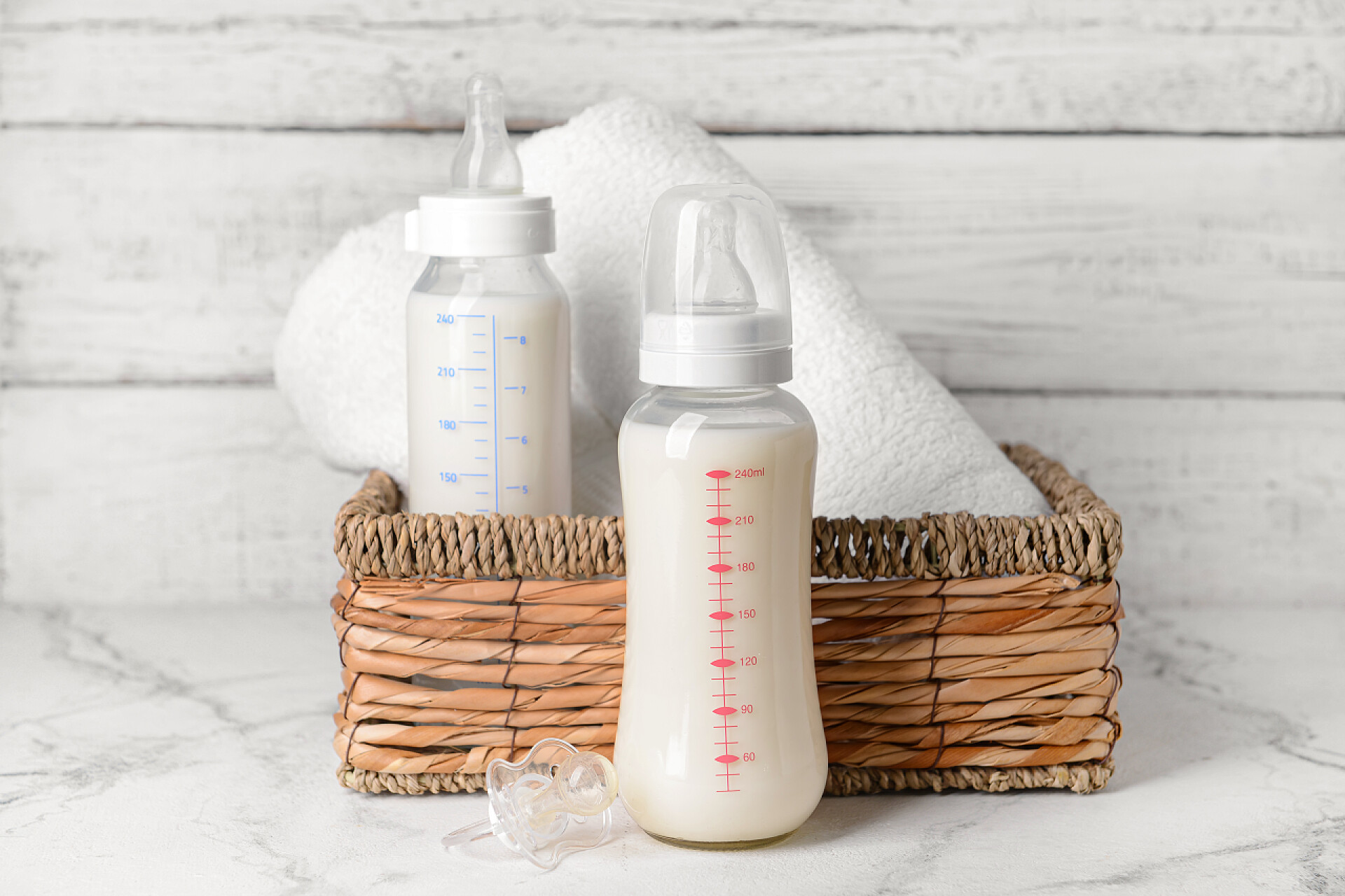 桌子上的奶瓶和竹筐桌上放一盒婴儿牛奶和毛巾