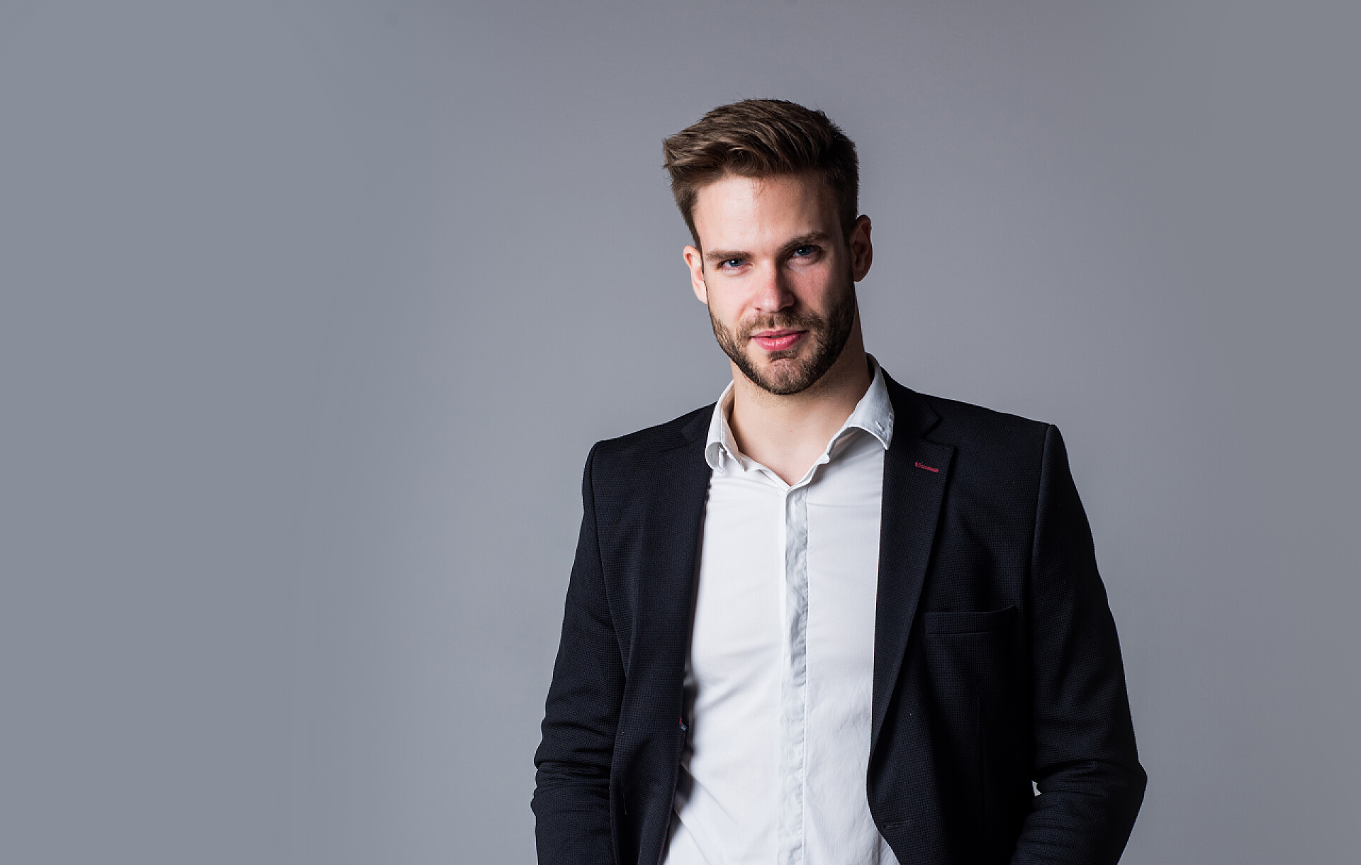 灰色背景墙的西装男人看起来很时髦发型整洁的很好。男性的美丽和时尚的外表。大胡子男人的正式办公室服装。光秃秃的英俊男子，头发蓬乱。理发师的概念。年轻自信的老板