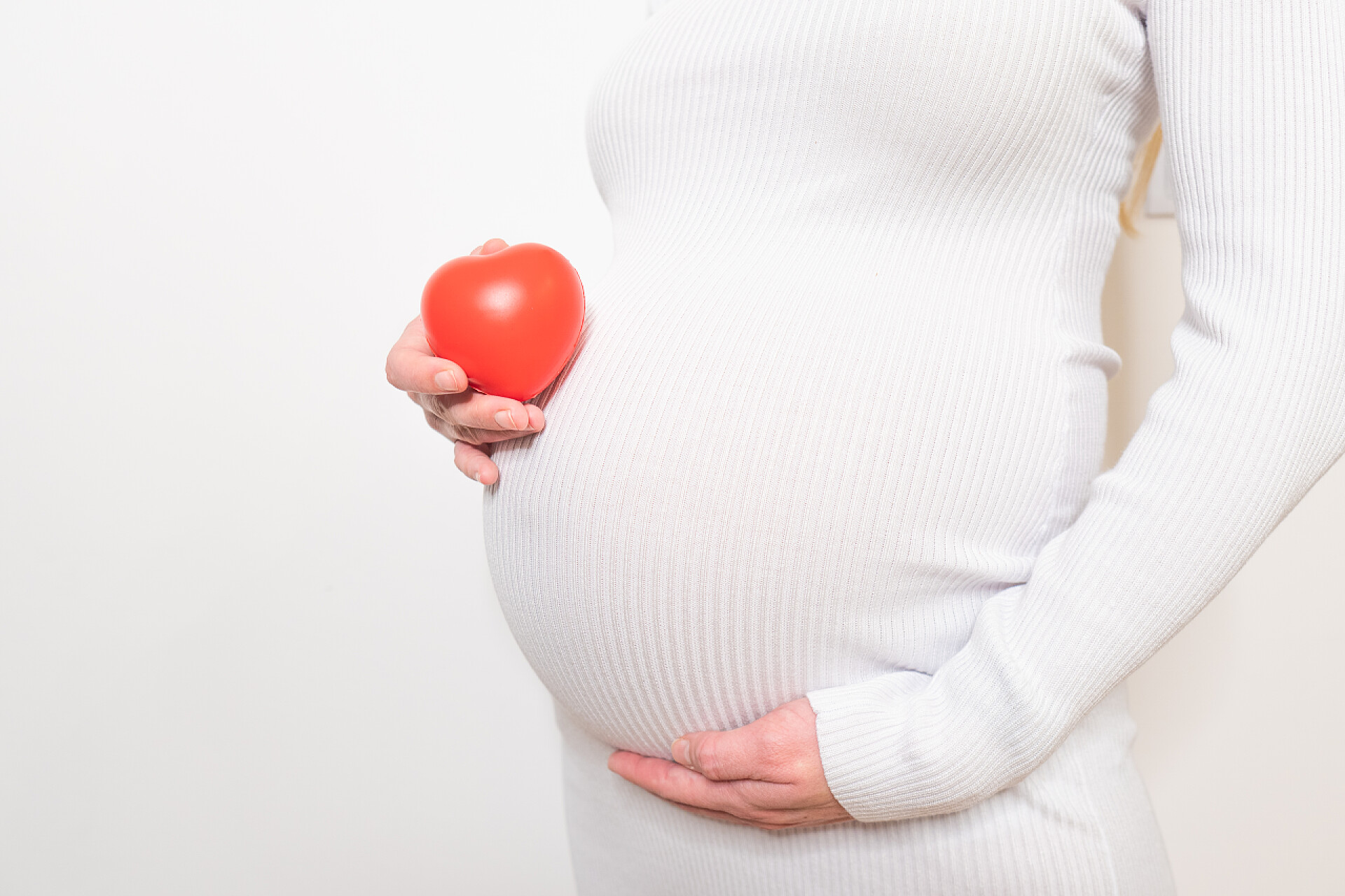 白色背景墙的一个孕妇拿着爱心