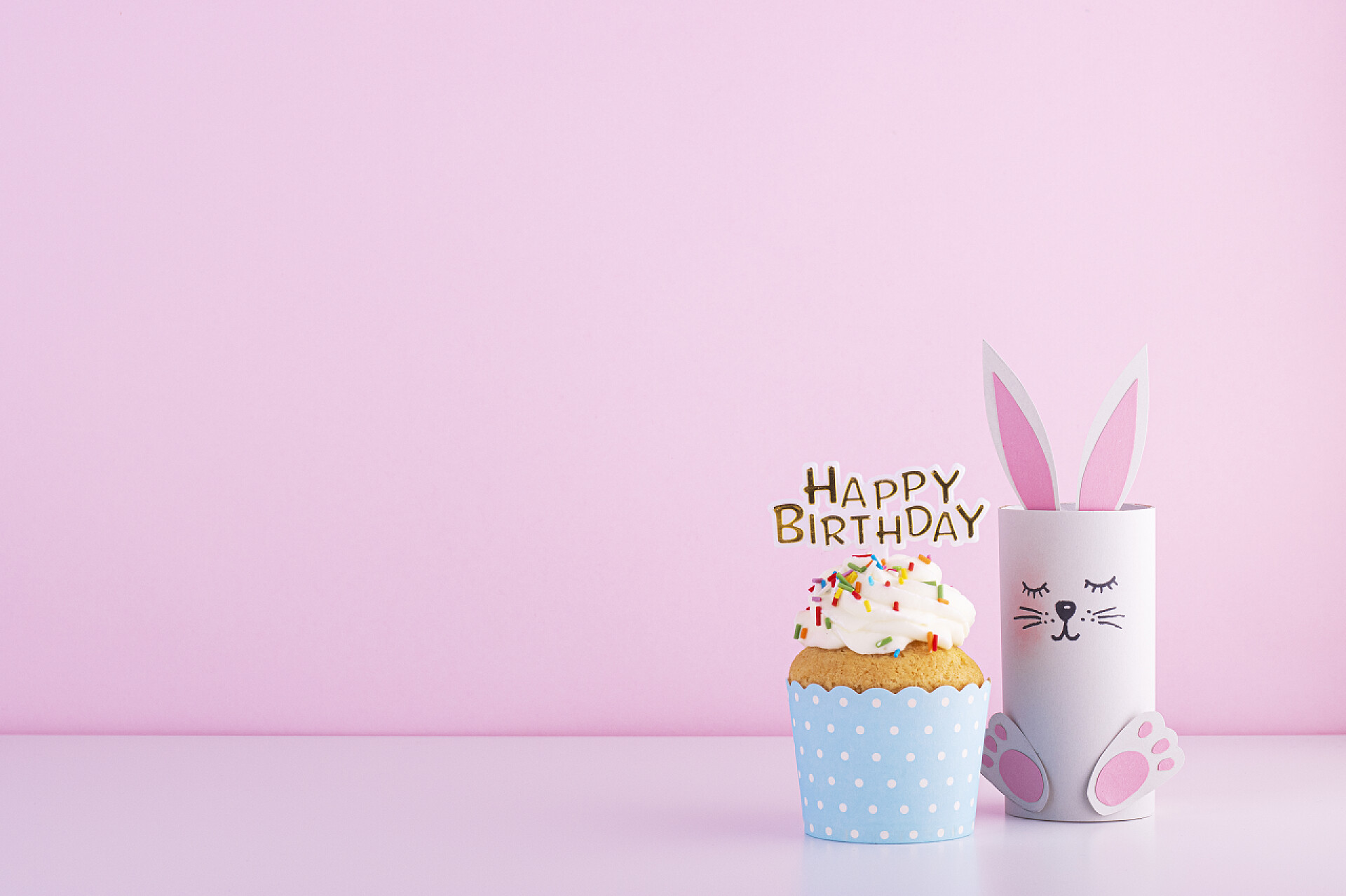 粉色背景前的这糕和礼物可爱的纸兔和美味美丽的蛋糕蛋糕生日粉红背景。生日宴会的背景