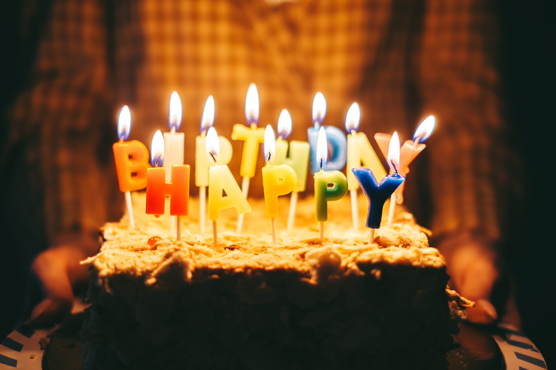 插着字母的蛋糕手里拿着点燃蜡烛的生日蛋糕的女人。高质量的照片