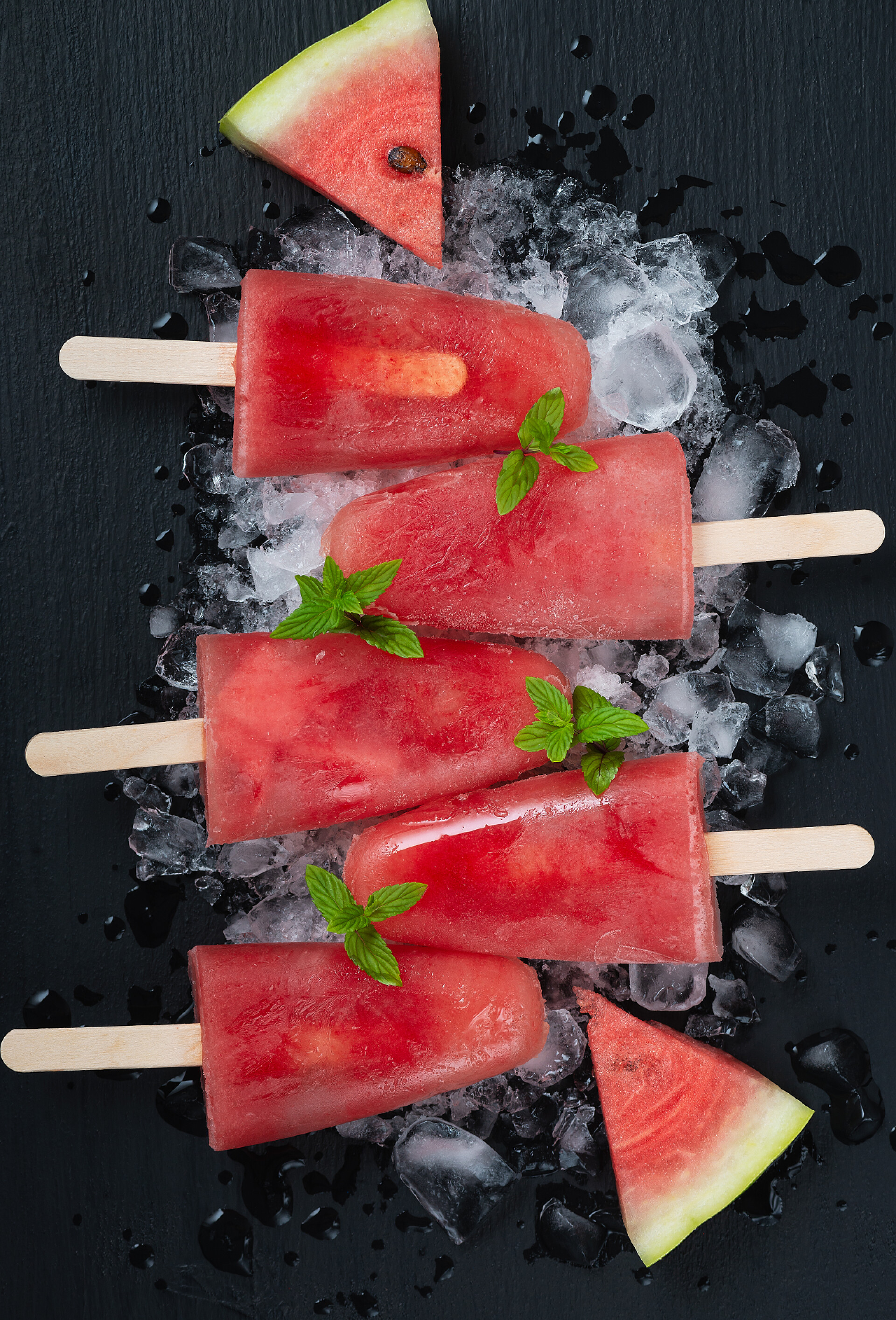 黑色桌子冰块儿上的西瓜口味的冰棍黑木桌上的西瓜冰淇淋