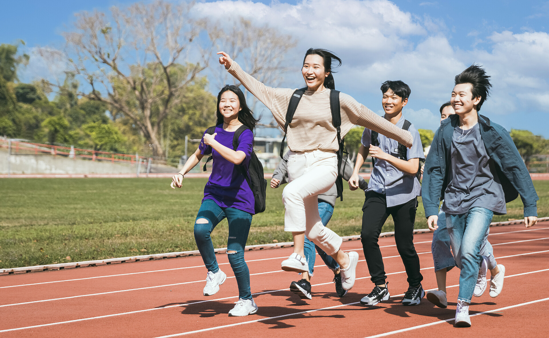 五个年轻人在操场上奔跑跑遍田野的快乐团组学生