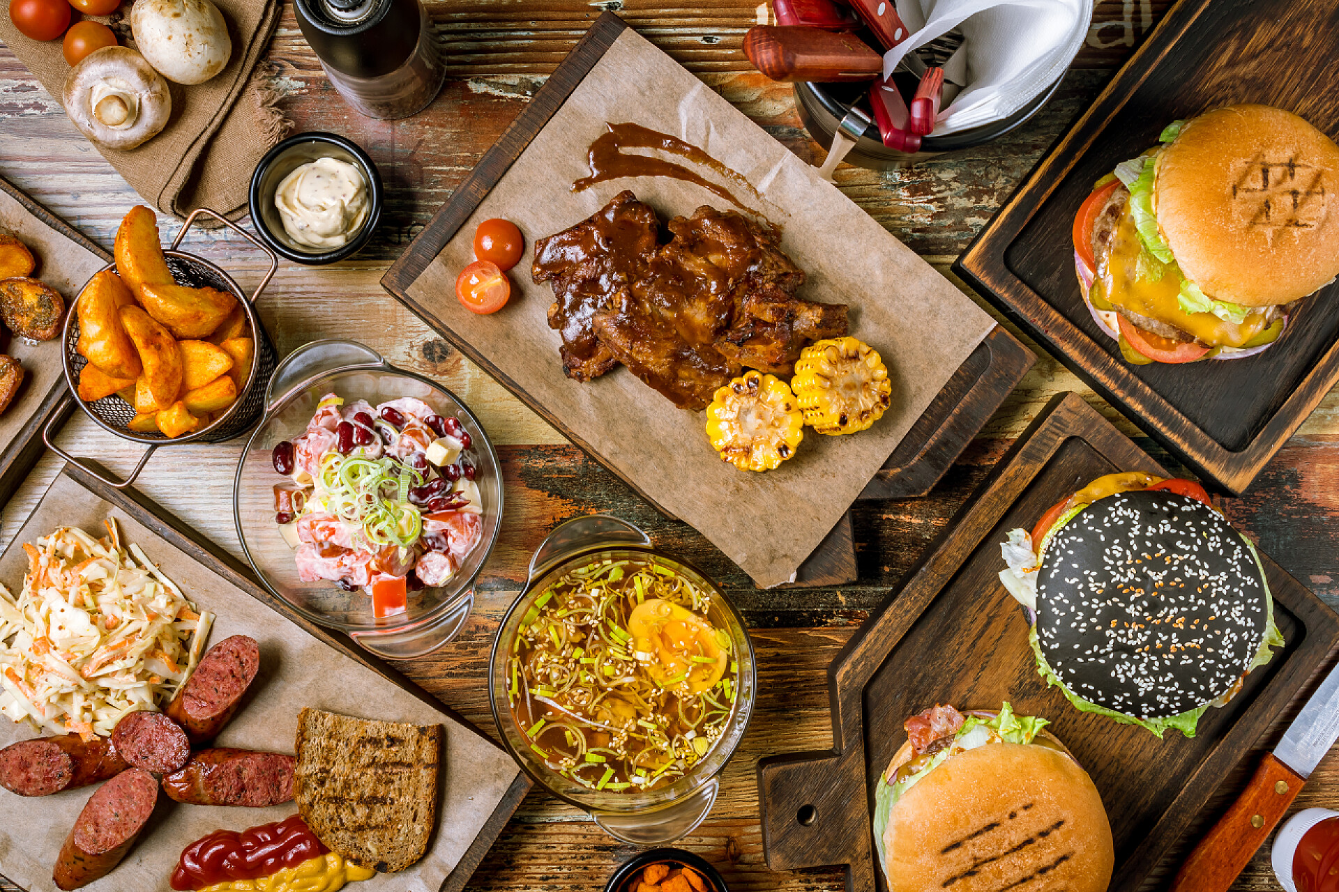 桌子上的各种快餐食物带汉堡包、薯条和烤肉的木制背景快餐套餐的顶部视图