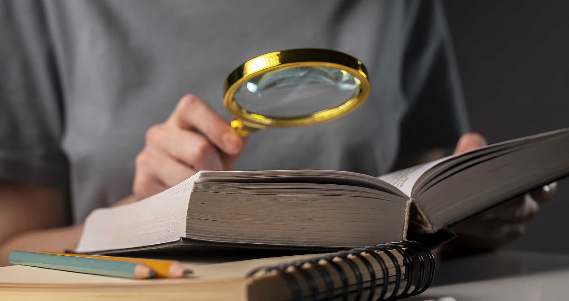 用放大镜查看书上内容的人女生手拿铅笔看书，晚上在饭桌上准备考试。教育概念