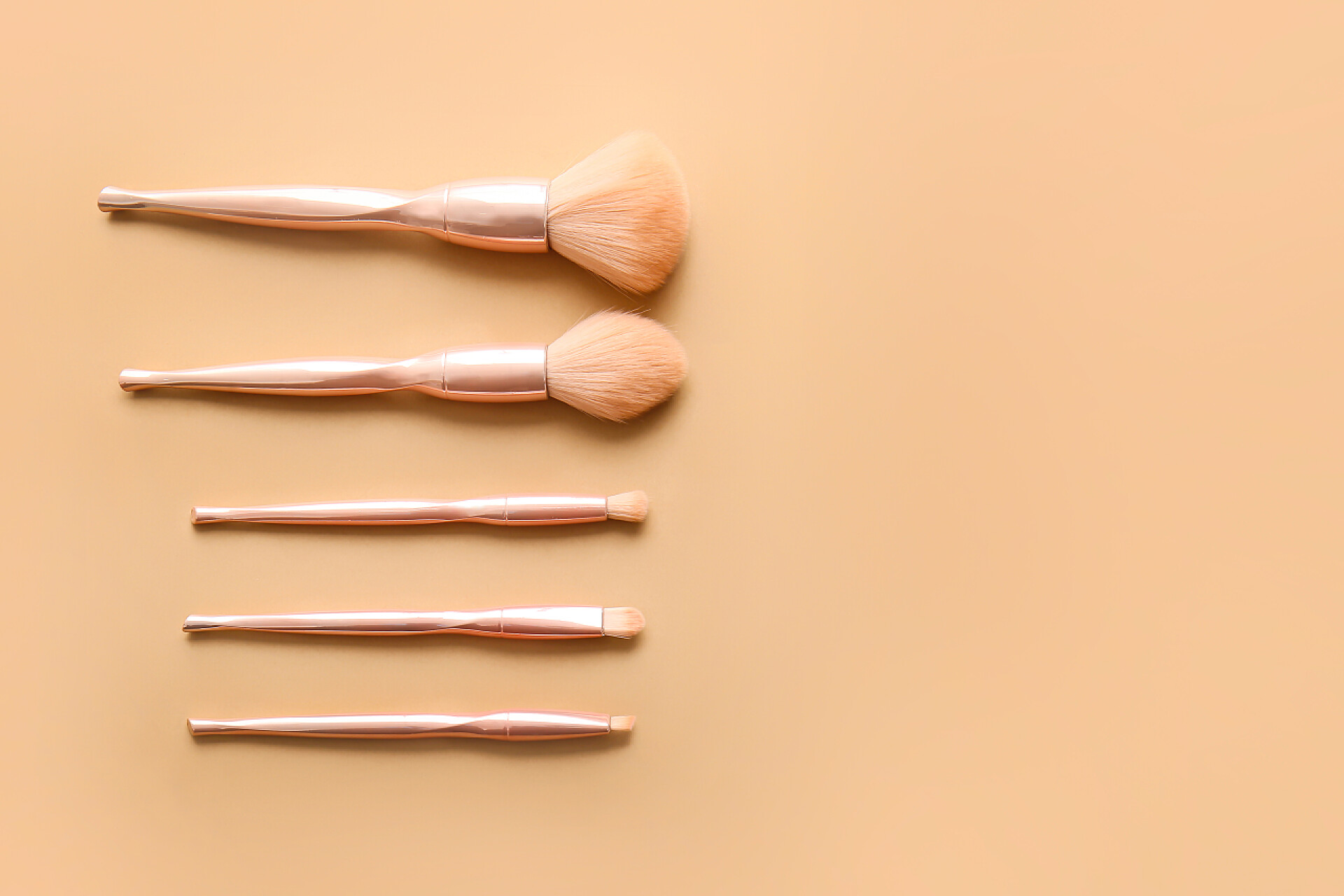 橙色桌子上的五种不同的刷子色系背景上的古色古香化妆品刷