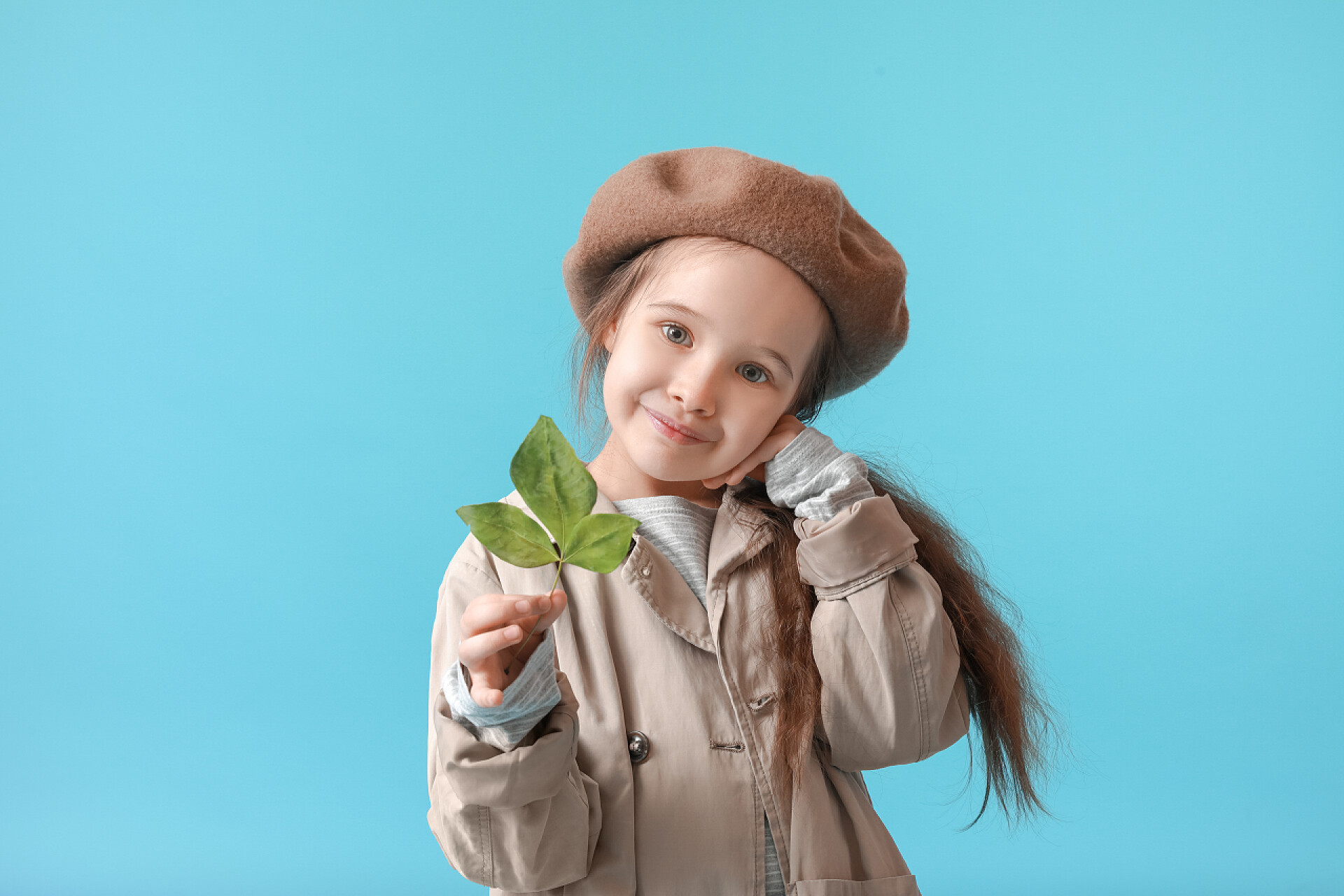 蓝色背景前的一个小女孩在拍照色彩艳丽的秋装小女孩