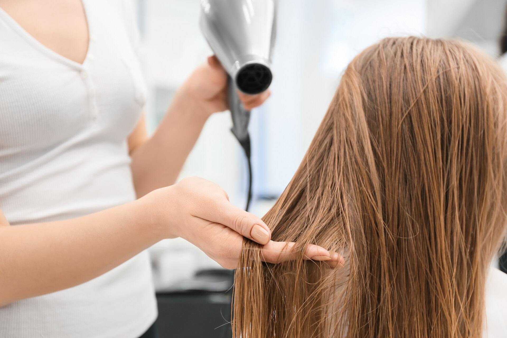 发型师在给客户吹头发女理发师在美容院、特写店吹干客人的头发