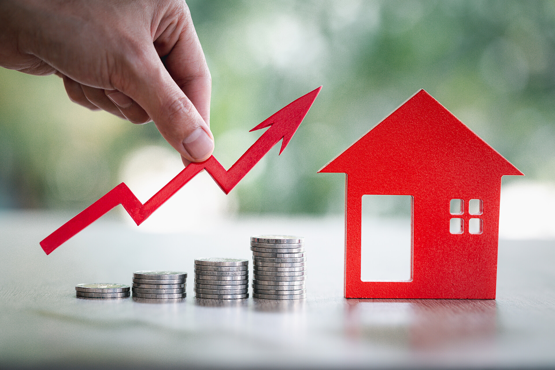 白色桌子上的投资金钱商人持有的图表超过了不断增长的房屋迷你。房地产投资和住房抵押贷款金融概念、投资财产、房地产、储蓄.