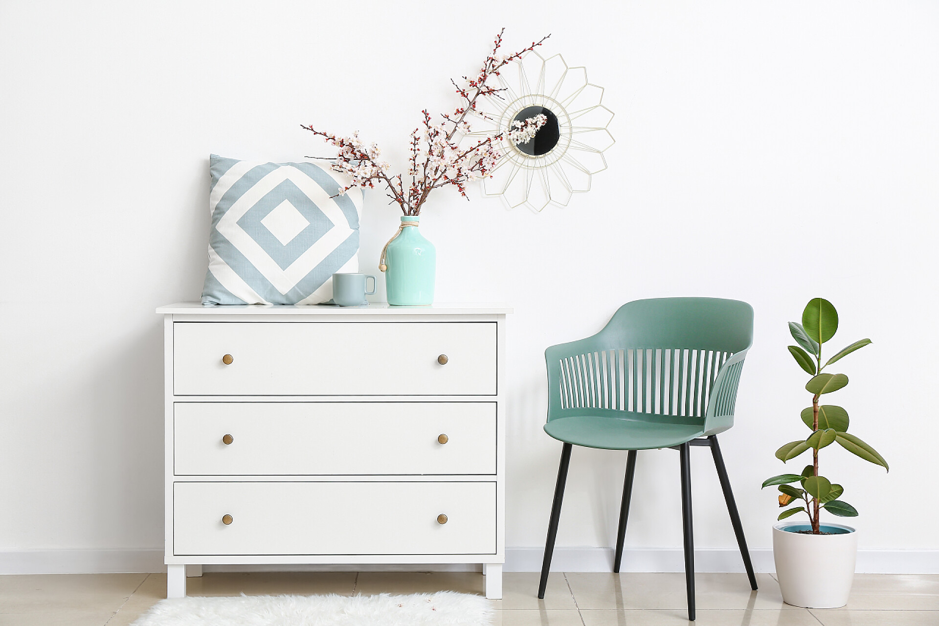 白色背景墙的家具房间里抽屉的箱子上放着美丽的花枝条和枕头