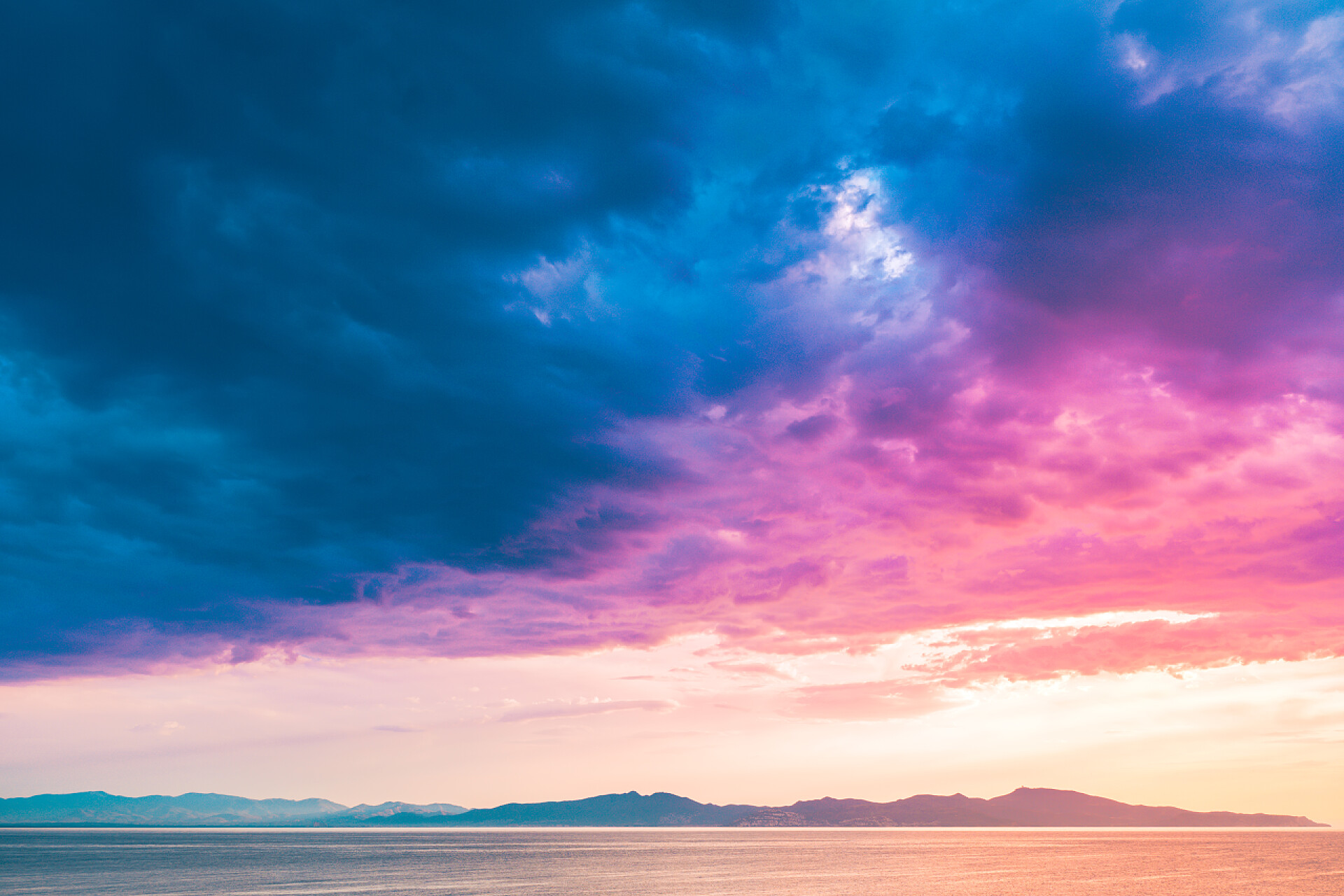 彩色天空下的海面海上灿烂美丽的日出.海面上一片五彩斑斓的天空.粉色和蓝色的云彩.