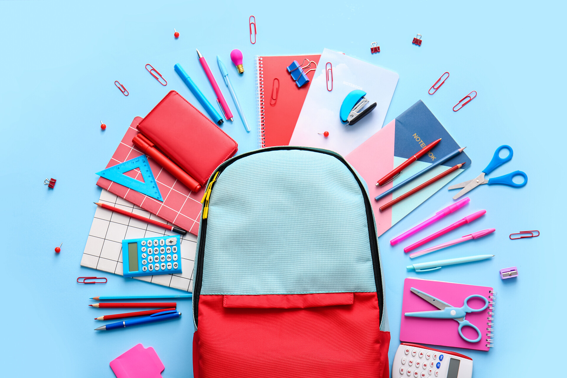 蓝色桌子上的学习文具彩色背景的学校背包和文具