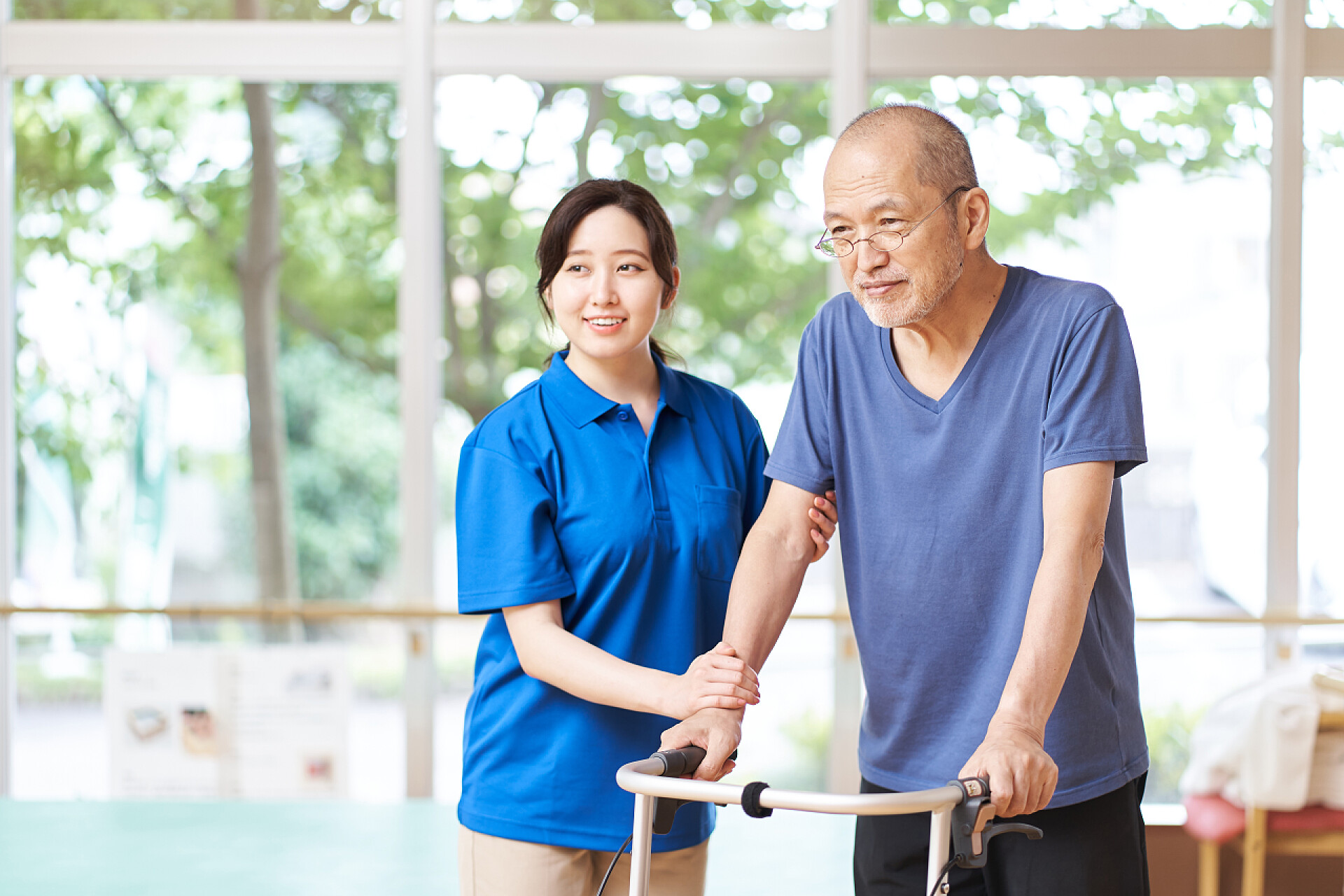 护工在帮助爷爷行走在助行器下行走的长者