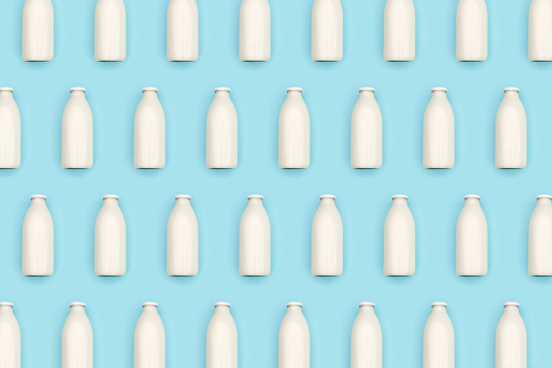 蓝色背景下的牛奶瓶图案由透明的玻璃瓶牛奶蓝色背景制成。平铺顶视图.