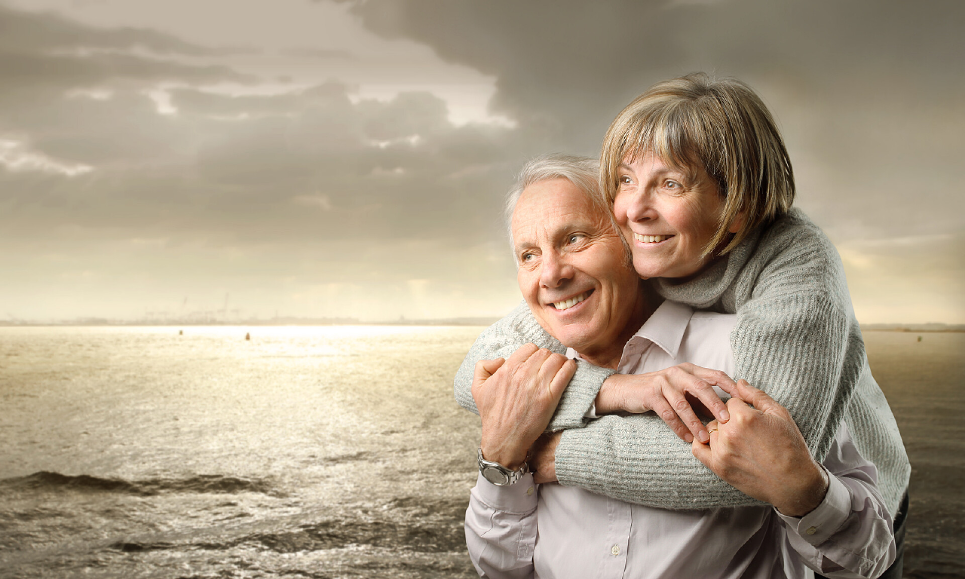 日落下在海边相互拥抱的老年人人物