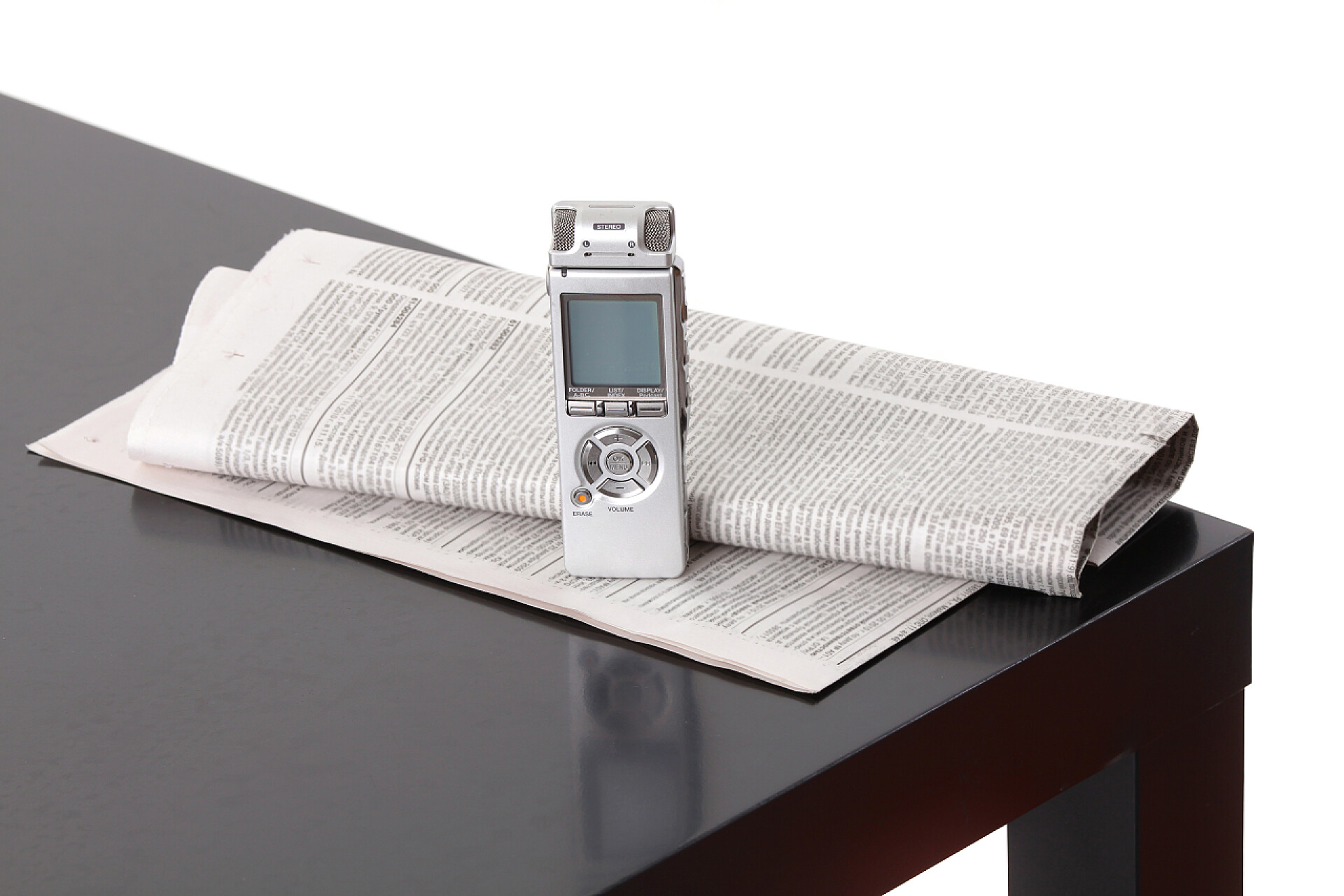 在白色背景黑桌子上的口述录音机和报纸新闻采集