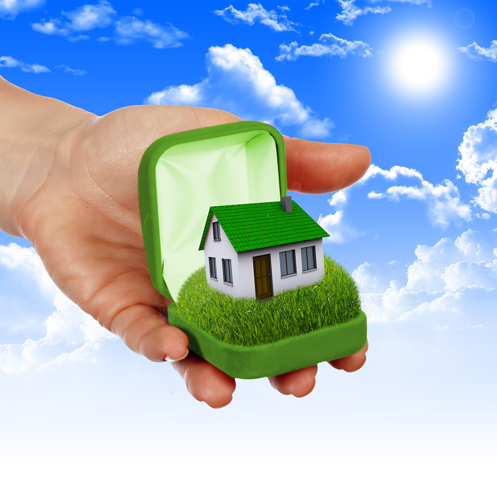 在蓝天下手中拿着绿色小房子的商人房地产