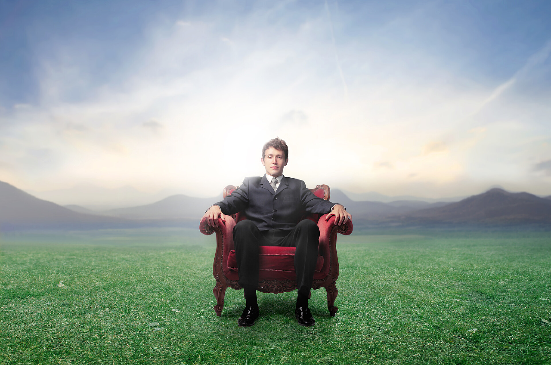 商务一片绿色的草地上坐在扶手椅上的商人