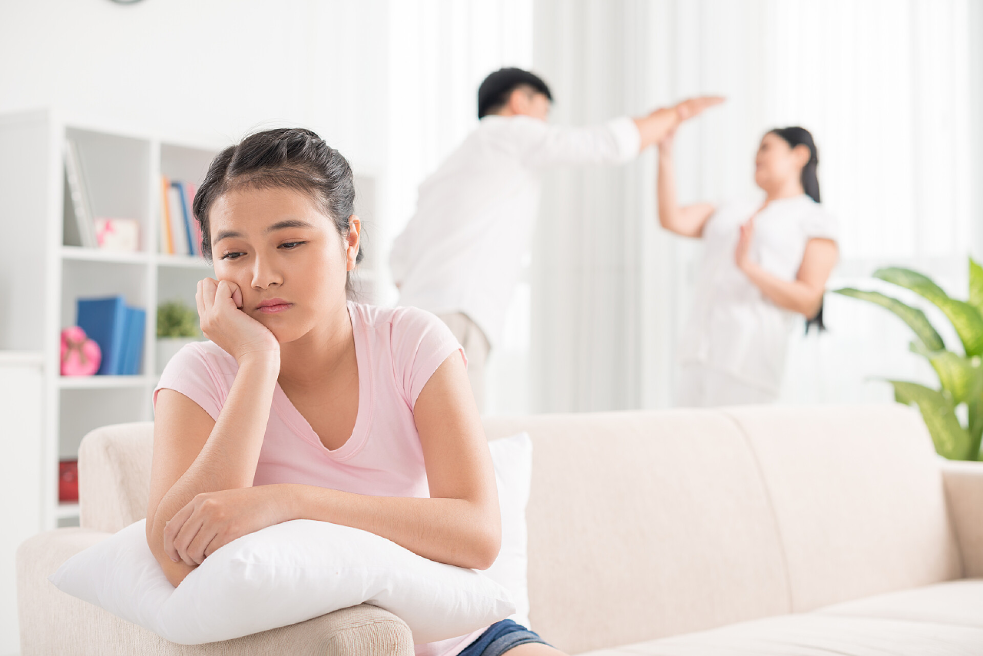 少女坐在沙发上难过的听着父母争吵的特写图像