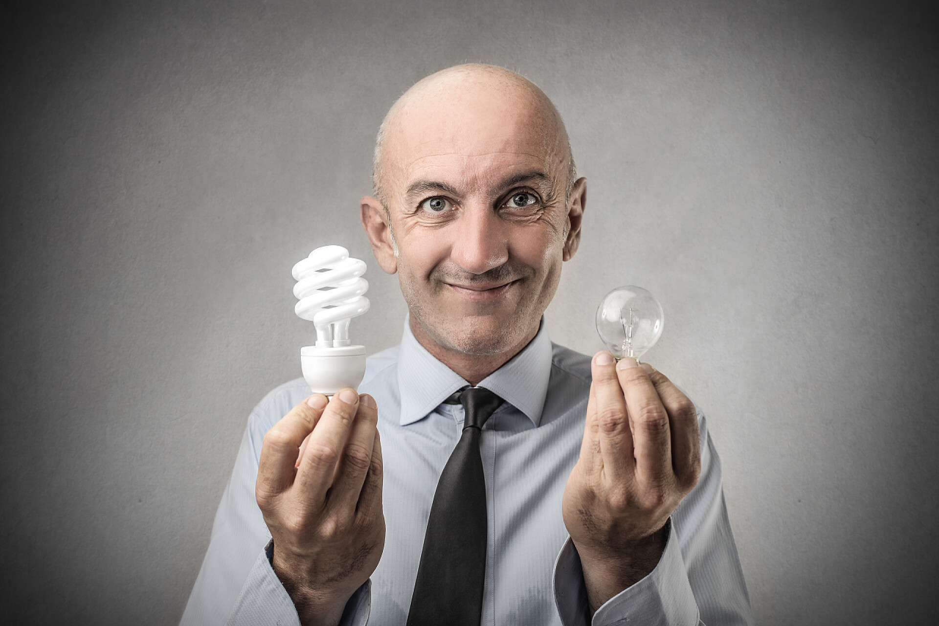 节能宣传商人拿着两个灯泡面带微笑商务商业