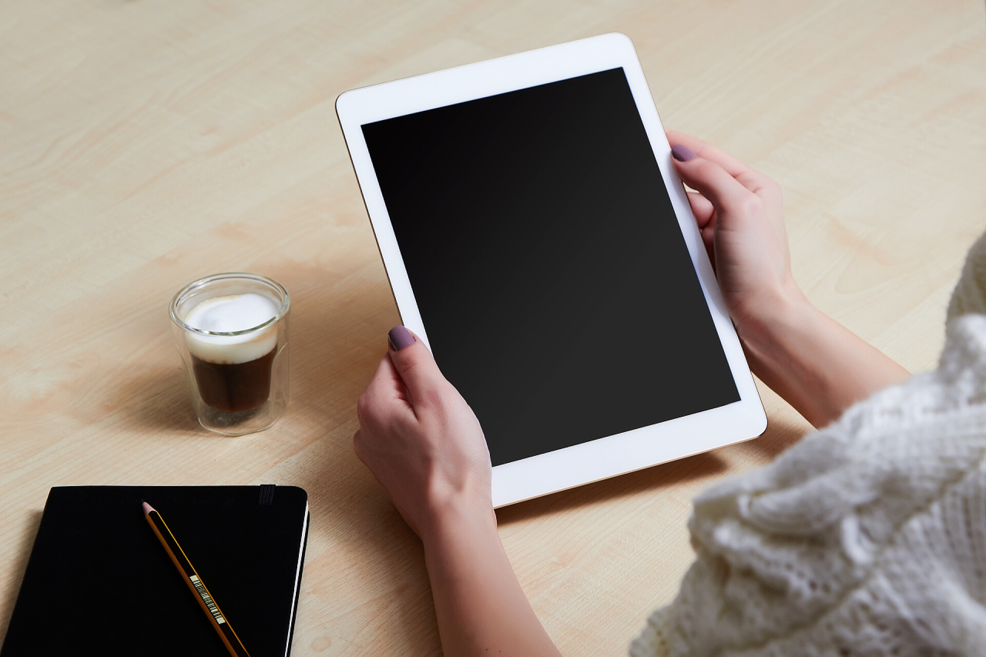 木质桌子前一个女人拿着平板电脑办公用品电子设备