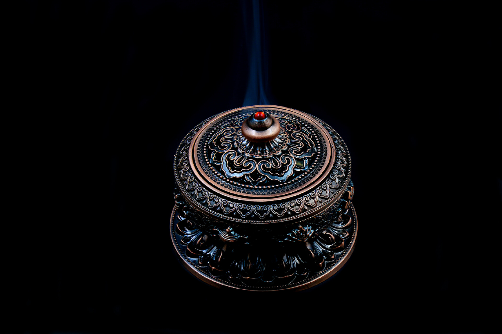 黑色背景上盘绕香烟的青铜香炉香薰