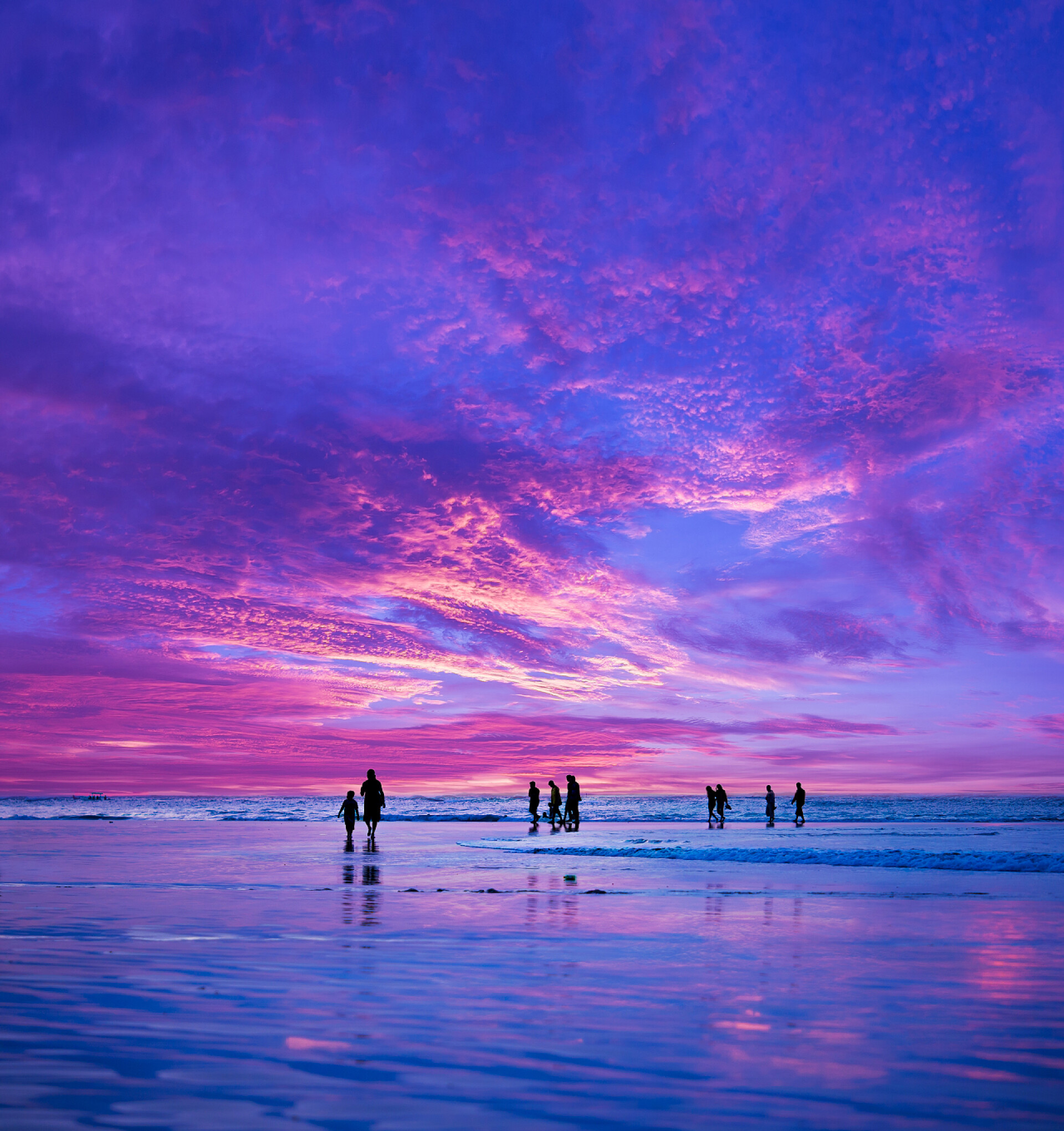 日落时分在巴厘岛库塔海滩的游客剪影度假旅游
