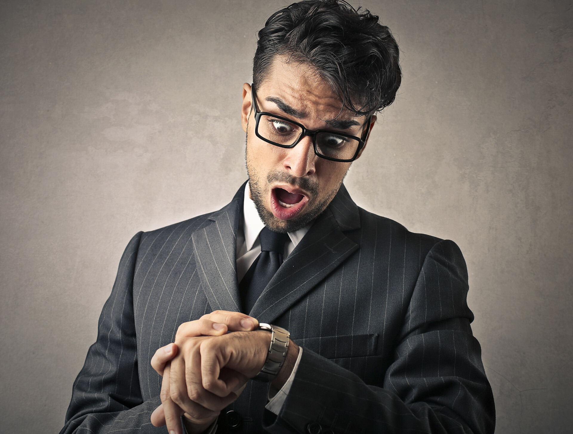 商务灰色背景上男人看着手表很惊讶