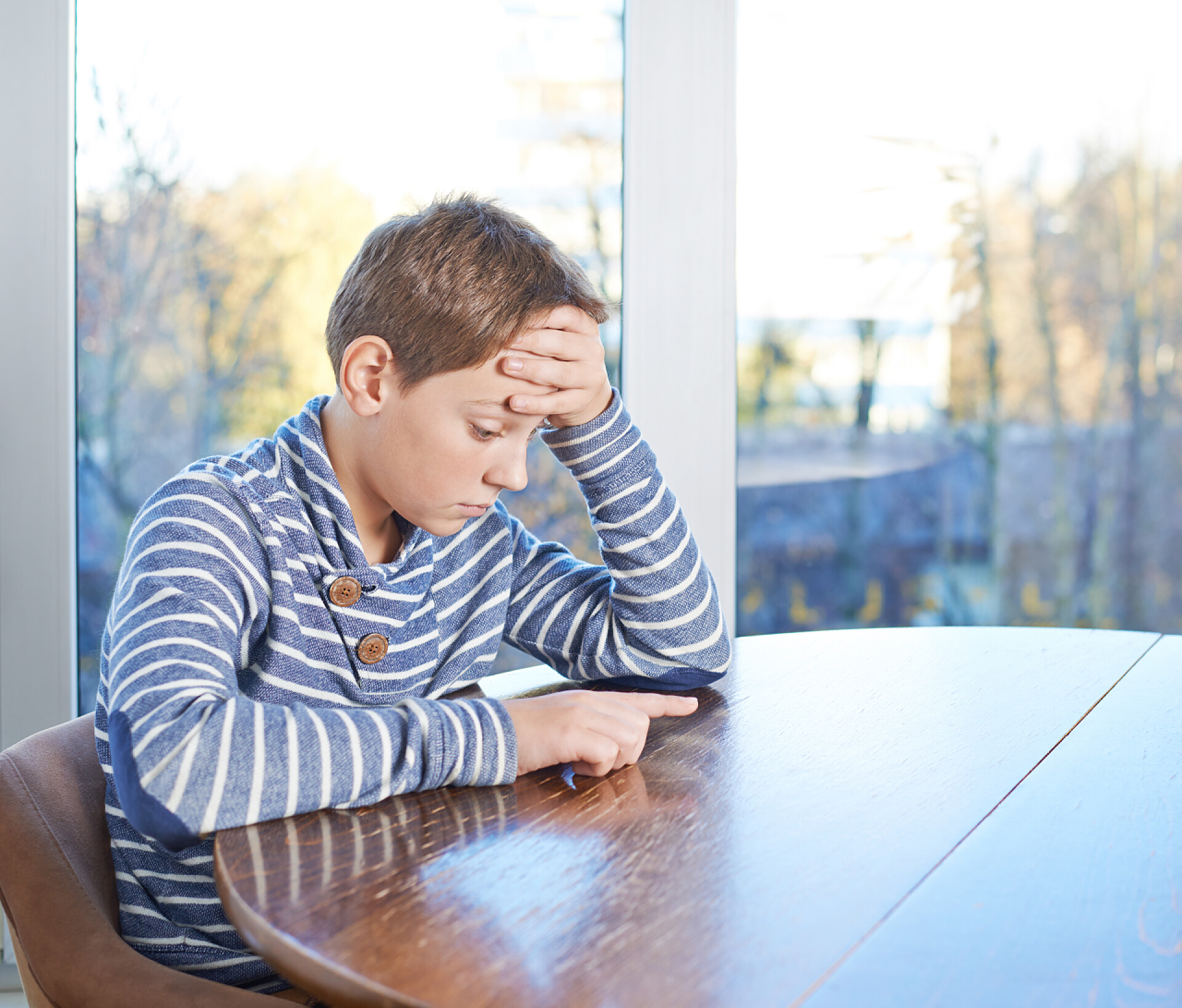 坐在桌边感到困惑和悲伤的孩童儿童