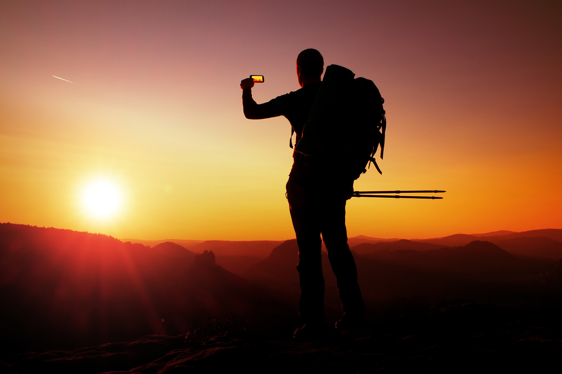 在山的顶峰徒步旅行者用智能手机拍照旅行