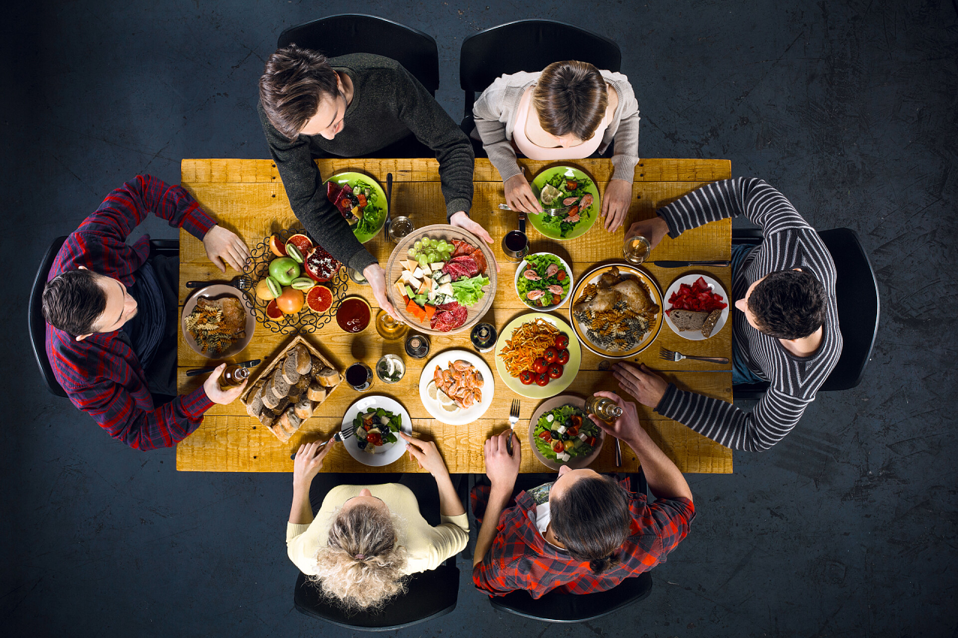 围绕桌子做的朋友的顶视图照片食物坐在木制复古桌子的朋友的顶视图创意照片。六人的朋友正在吃晚饭。他们盘满了美味的饭菜和饮料的玻璃杯