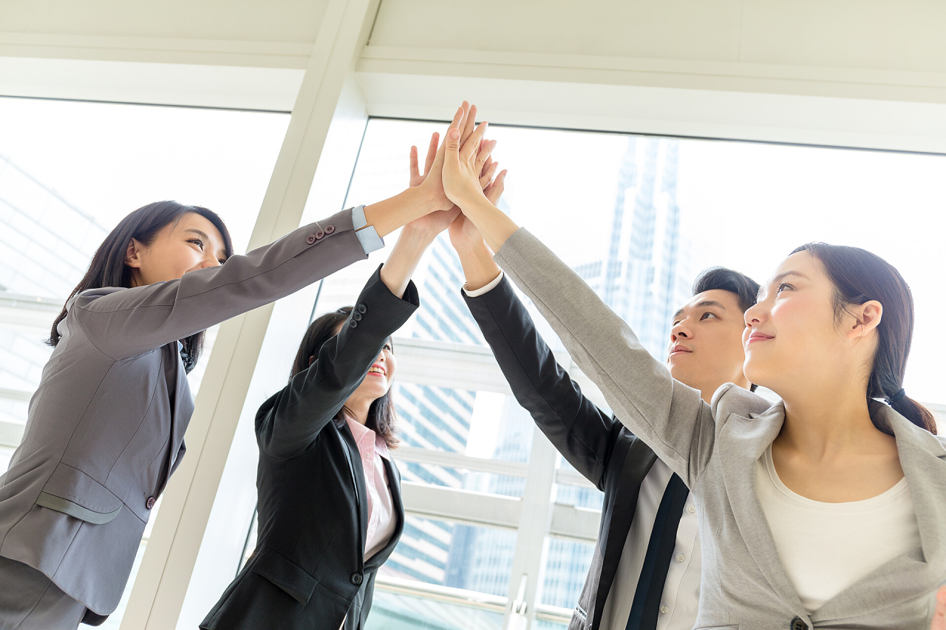 一群年轻的亚洲业务人加入的手一起庆祝商务团队
