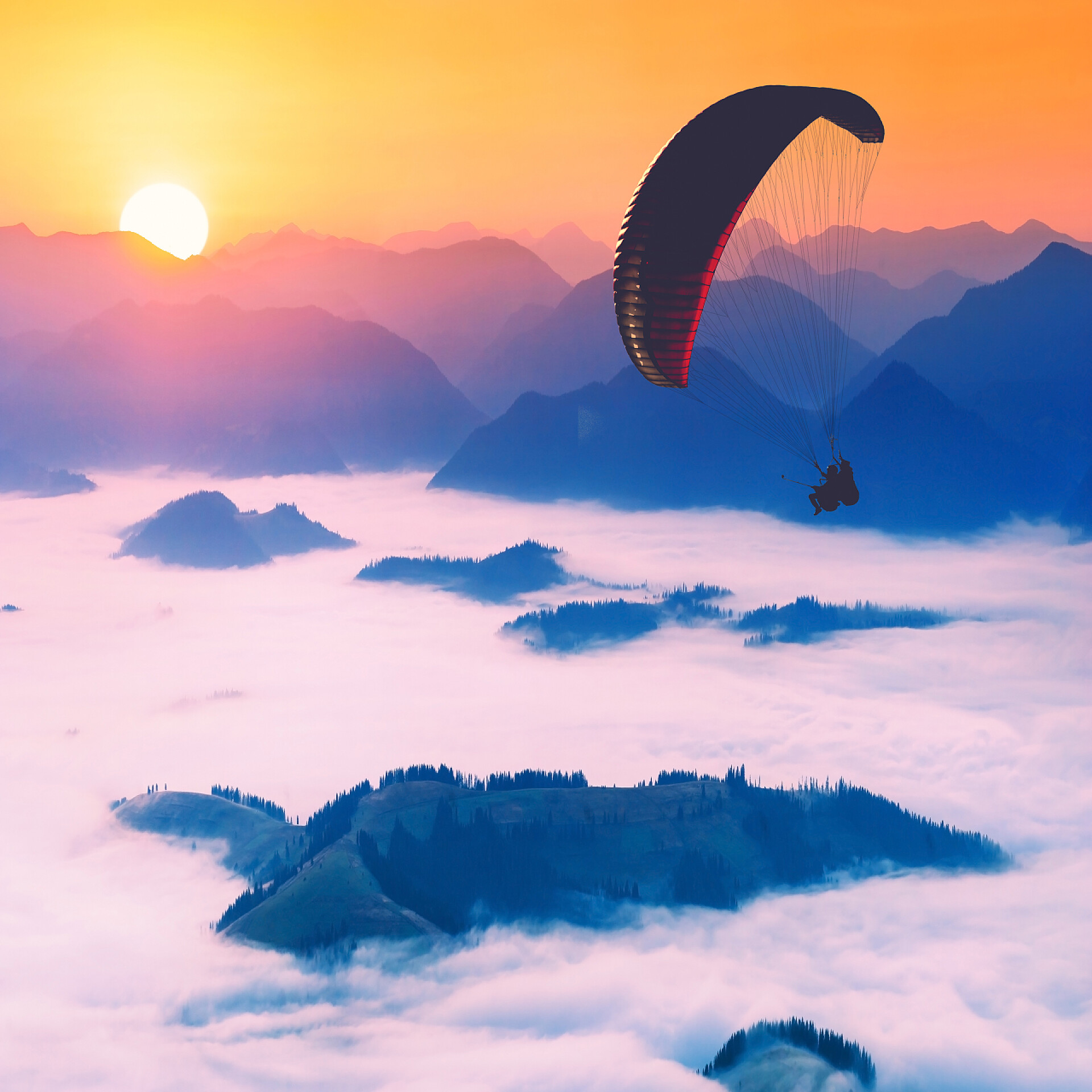 高山日出时分的云海上操控滑翔伞的运动员