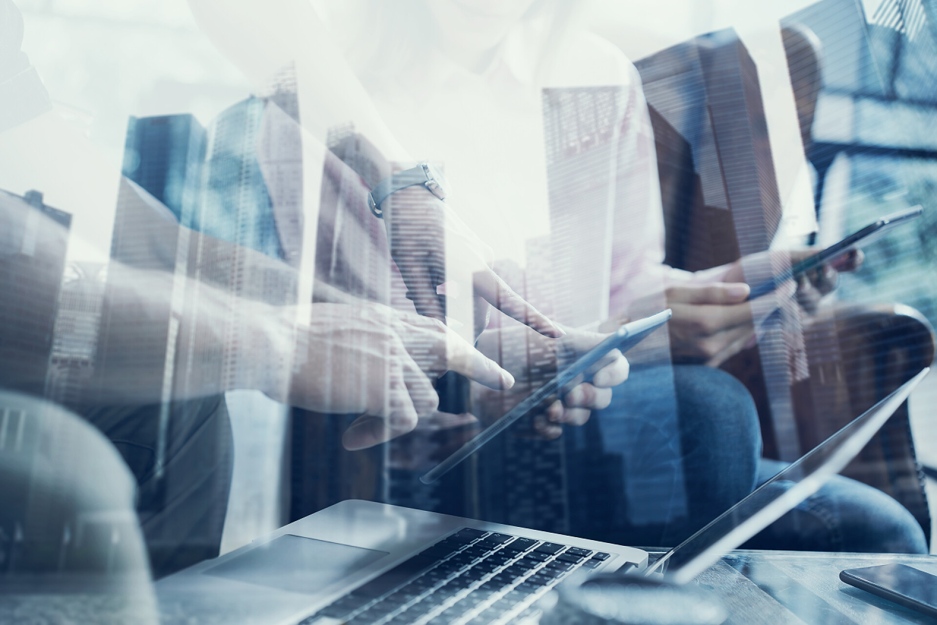 双重曝光 城市背景下年轻同事一起工作二次曝光的年轻同事一起工作在现代办公的新启动项目。商务人士使用的移动设备。摩天大楼在模糊的背景。水平的特写