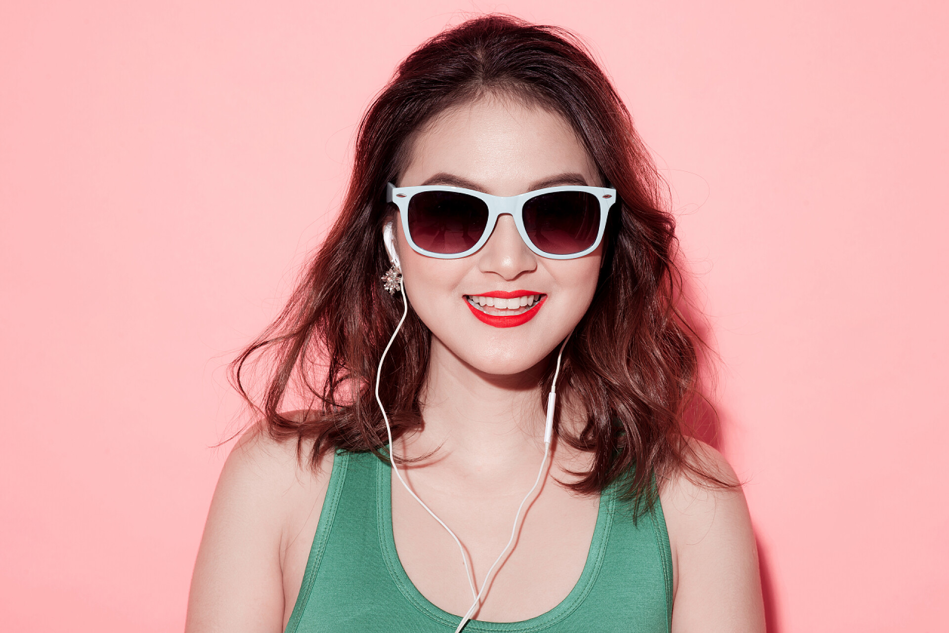 粉色背景下听音乐的年轻活泼开朗女孩