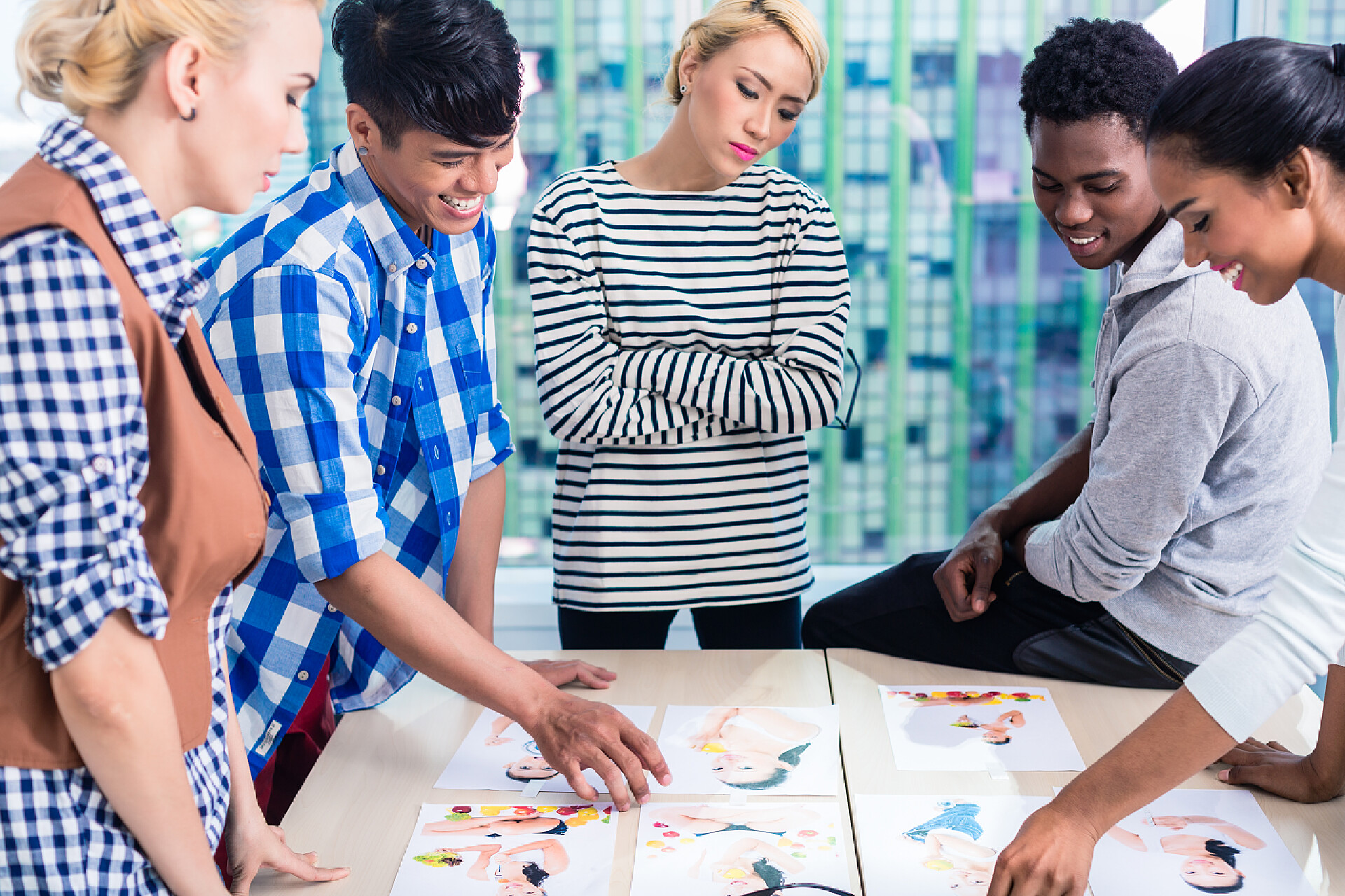 商业广告代理团队开会讨论选择桌子上的图片方案