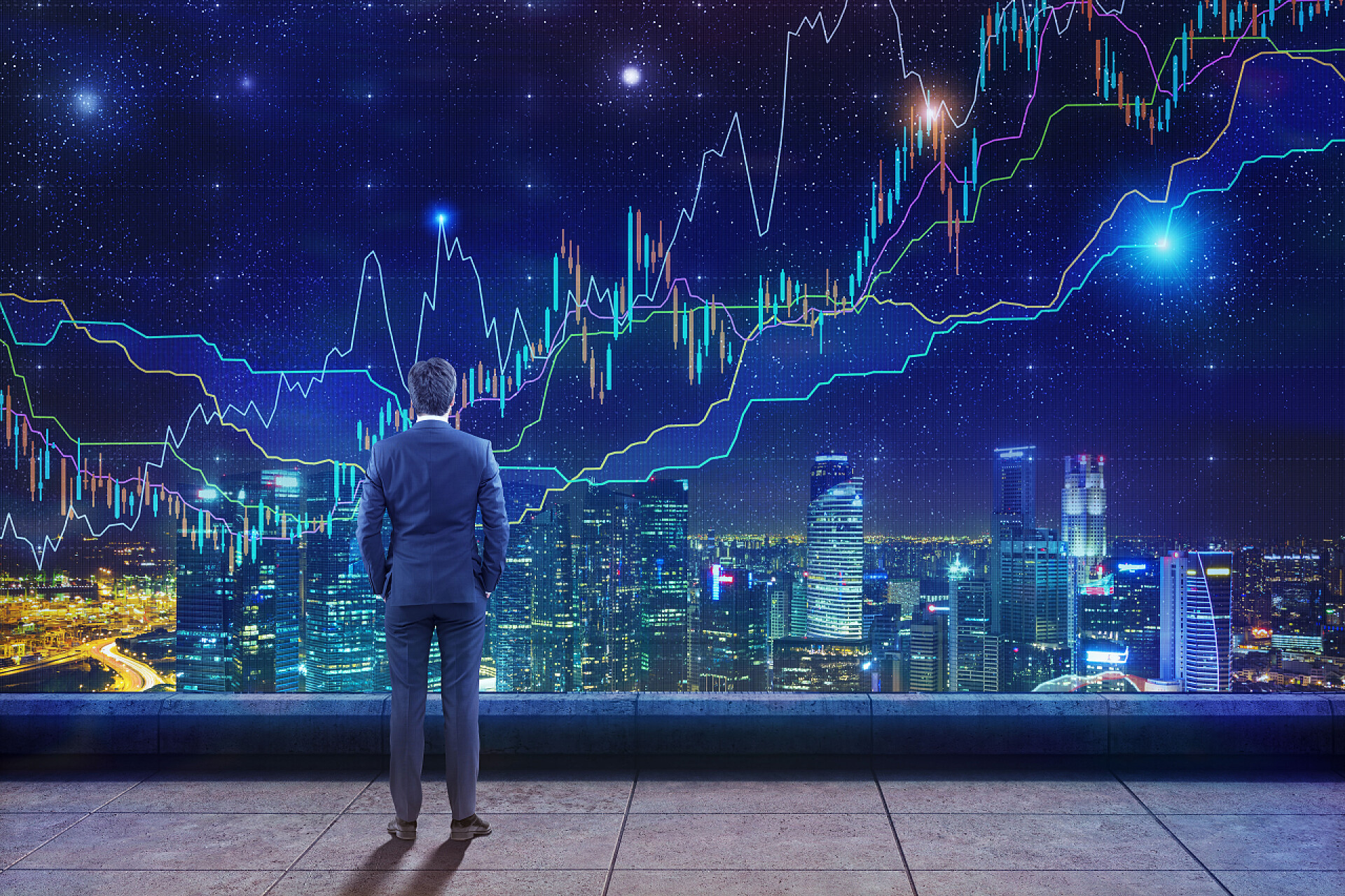 商务男士站在屋顶双手插在口袋里看着夜空中的城市和股市走势图的融合